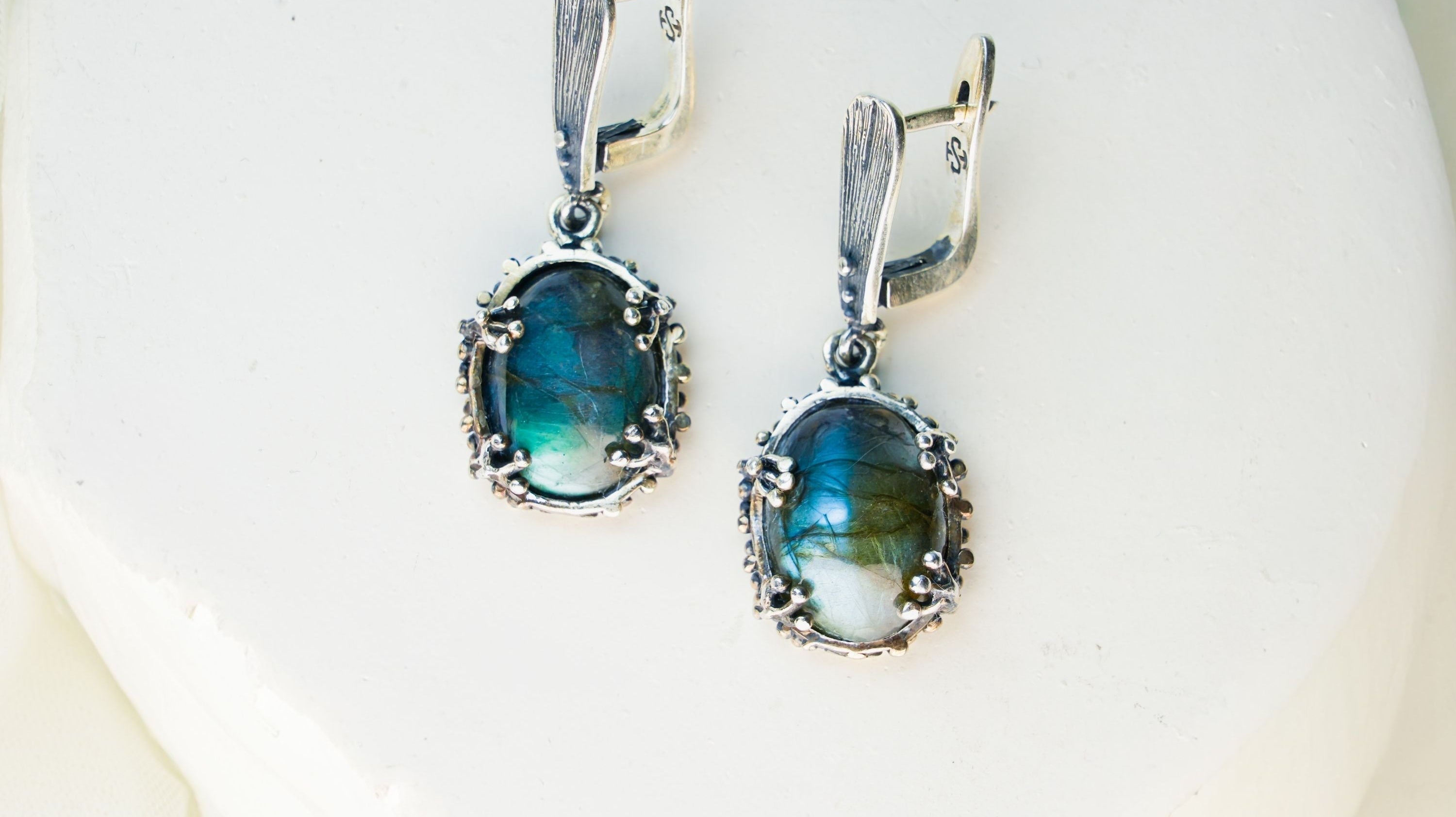 Handcrafted sterling silver earrings with iridescent blue-flash labradorite gemstones, featured in AKRA's guide to magical stones.