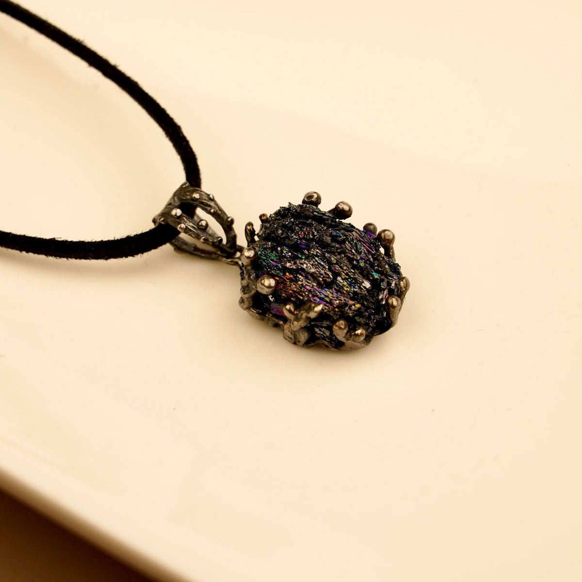 Raw black obsidian pendant in handcrafted sterling silver on a black cord, showing the natural iridescent surface of the stone
