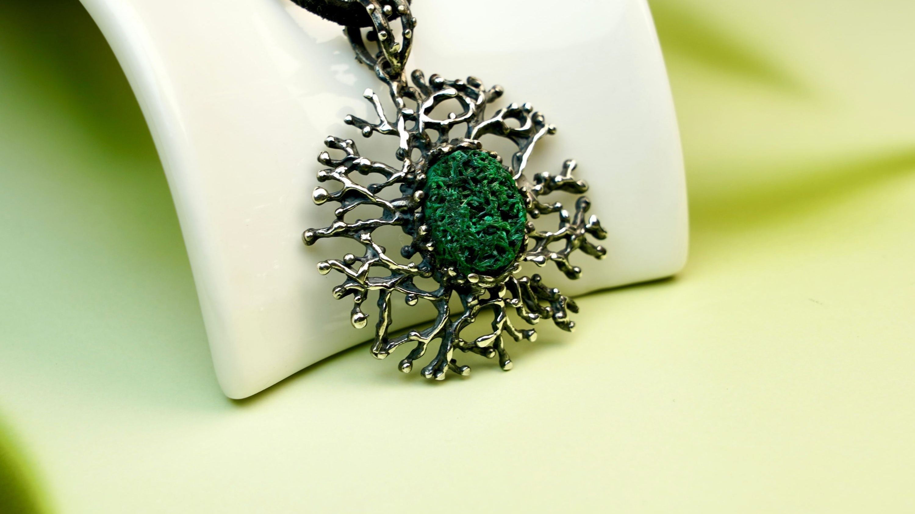 Handcrafted malachite pendant by AKRA, inspired by forest magic and Georgian craftsmanship, featuring a raw green gemstone in a sterling silver coral-style setting.