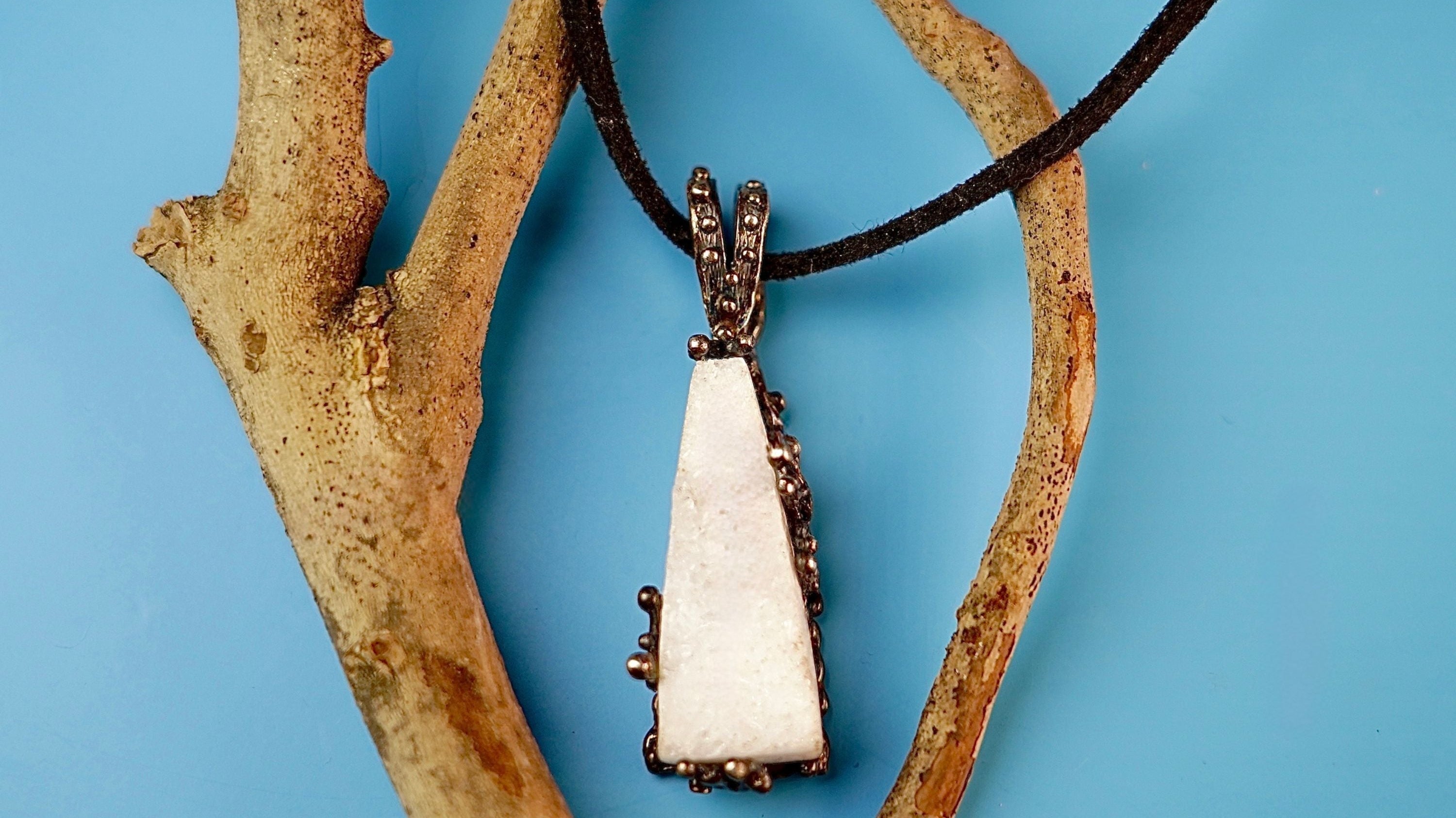 Raw white moonstone pendant necklace hanging on a natural wooden branch close up