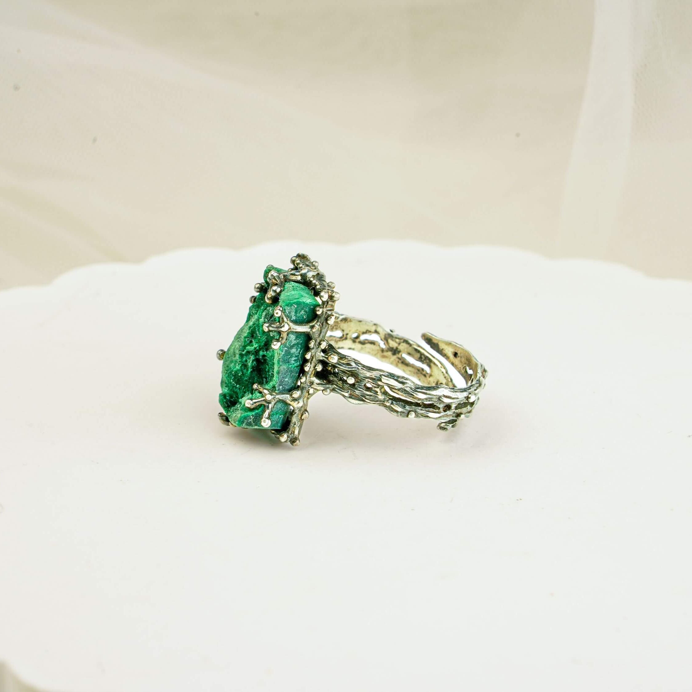 Bohemian style silver malachite ring displayed on a white aesthetic pedestal