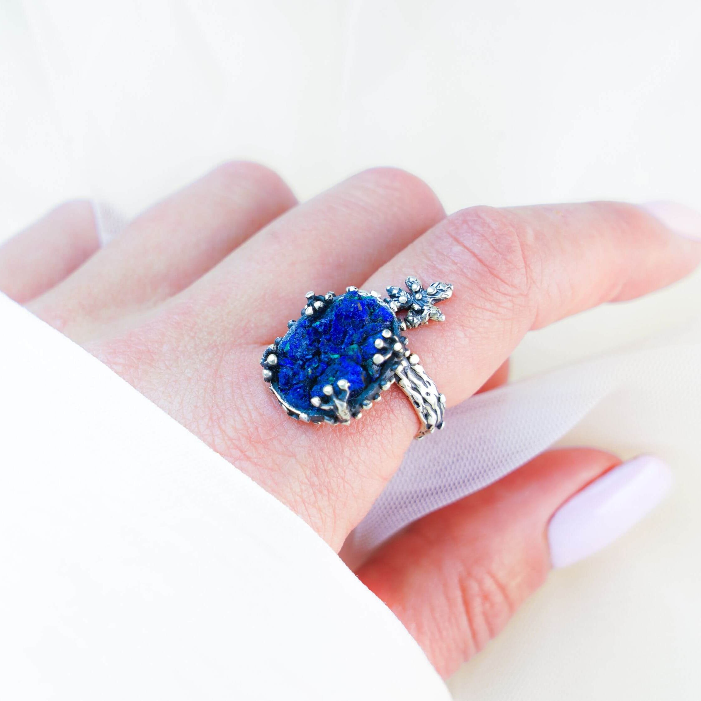 Statement lapis lazuli ring worn on finger showing the rich blue stone and nature-inspired silver wrap