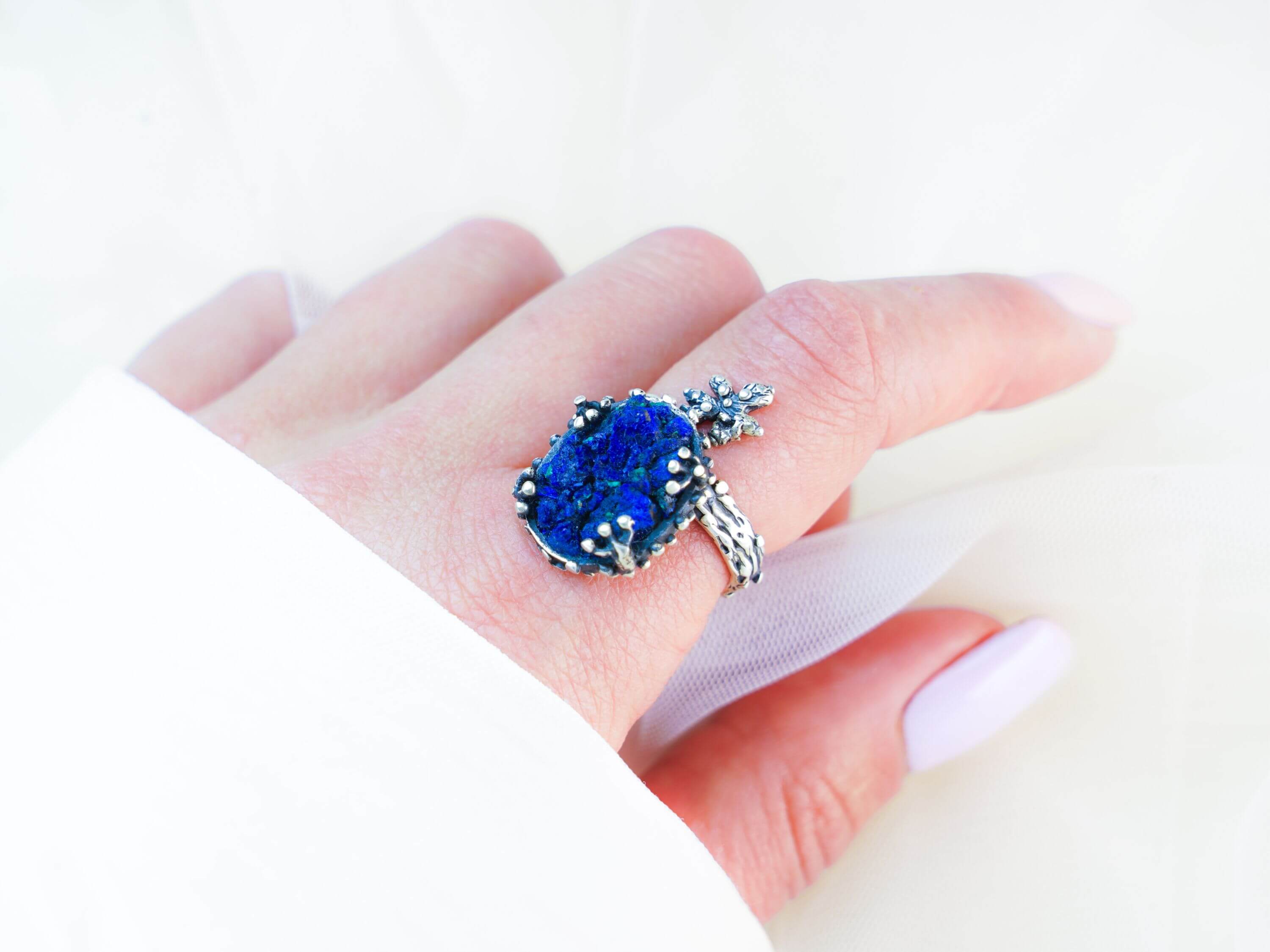 Statement lapis lazuli ring worn on finger showing the rich blue stone and nature-inspired silver wrap