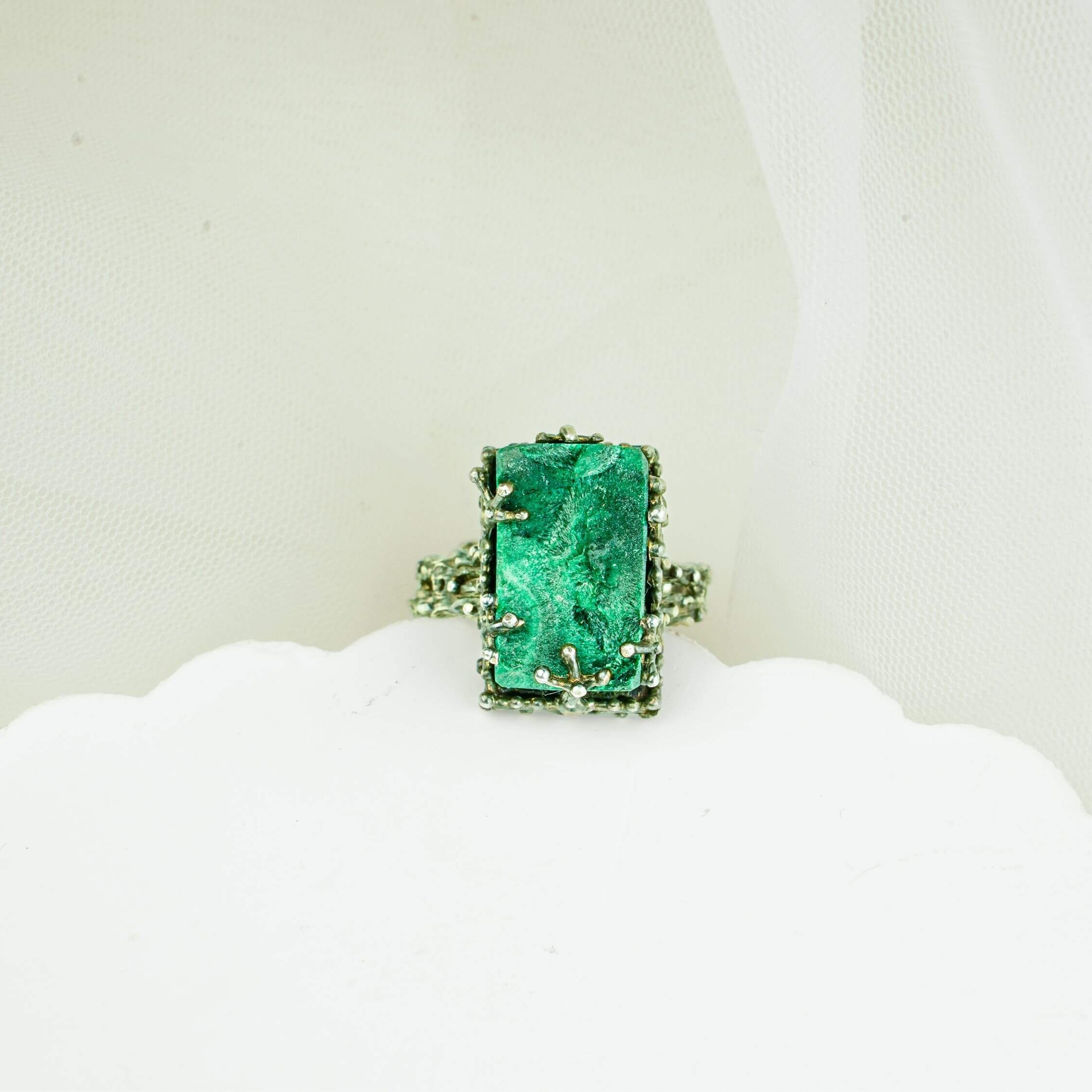 Close-up of natural green malachite texture and ornate handcrafted silver ring frame