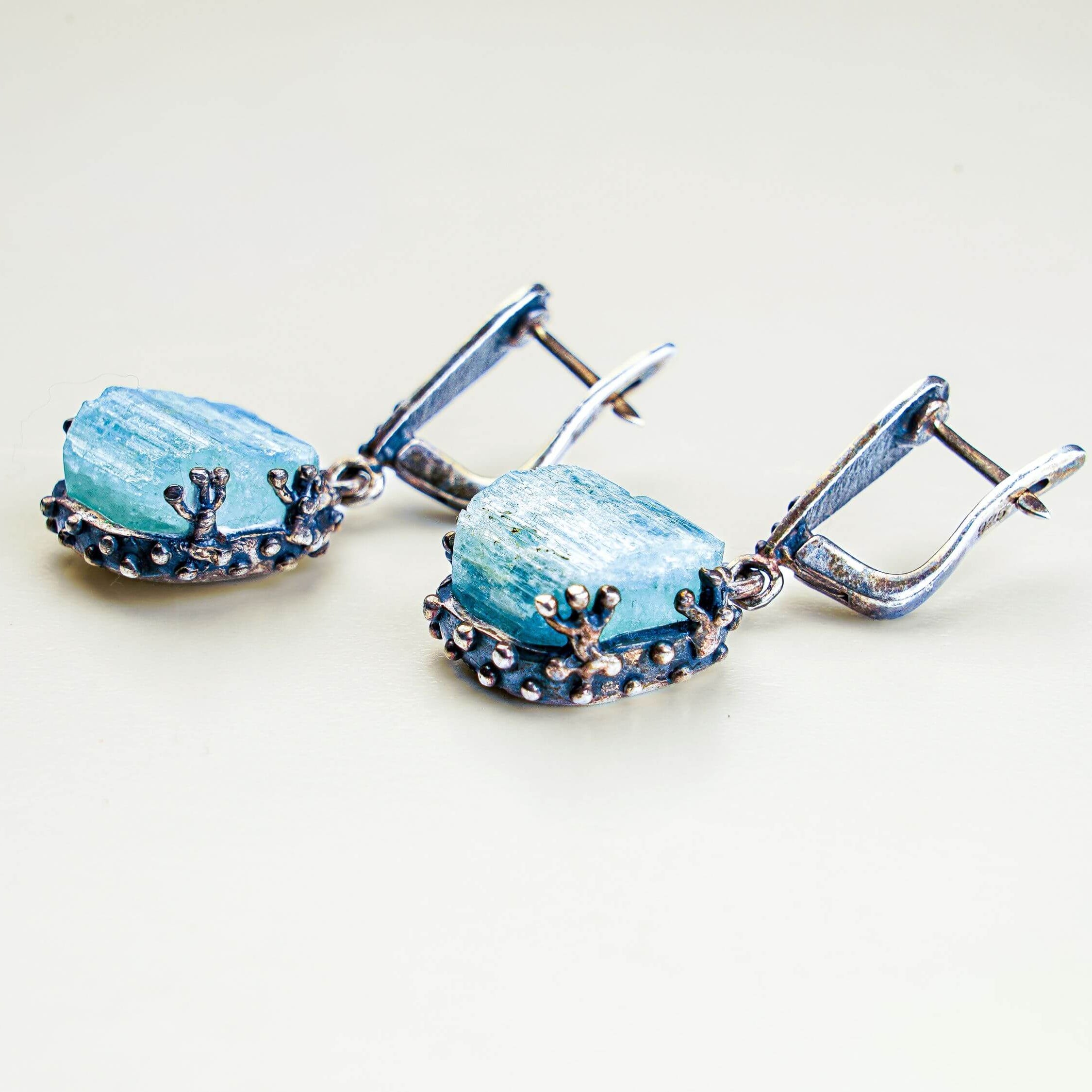 Close up aquamarine earrings raw crystal texture detail silver setting
