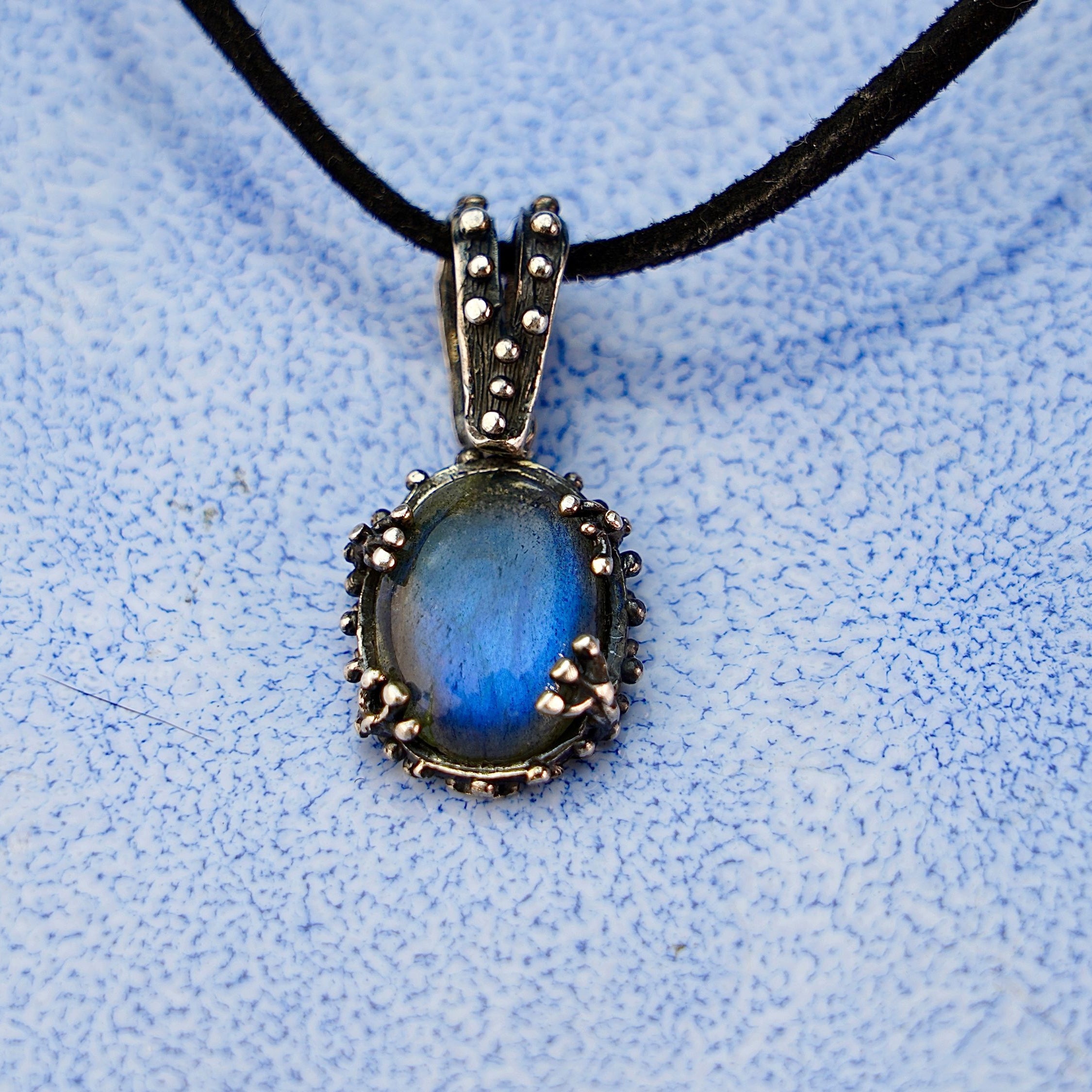 Close up labradorite pendant blue flash iridescent stone detail silver setting