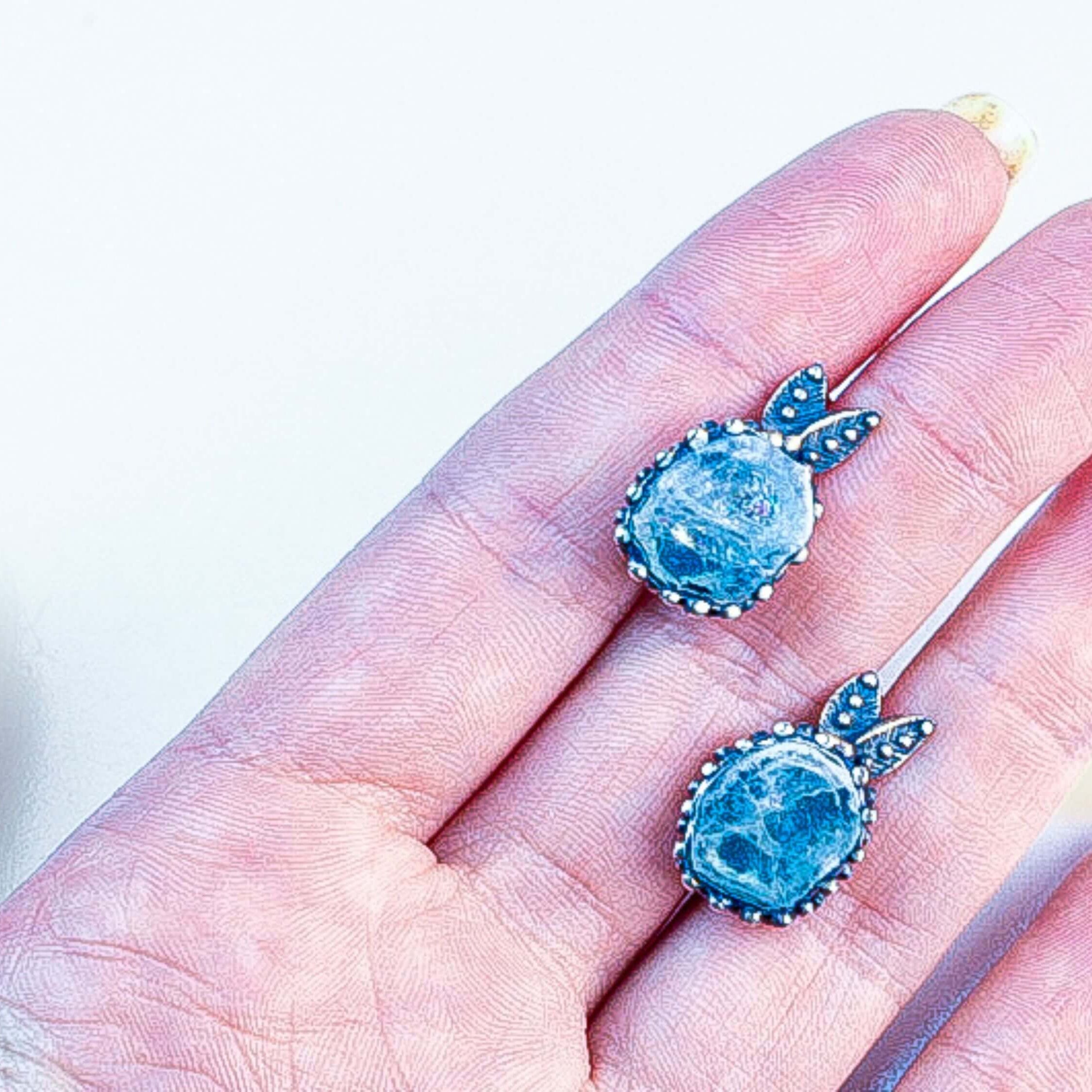 A pair of handcrafted aquamarine earrings held in hand to demonstrate scale and craftsmanship