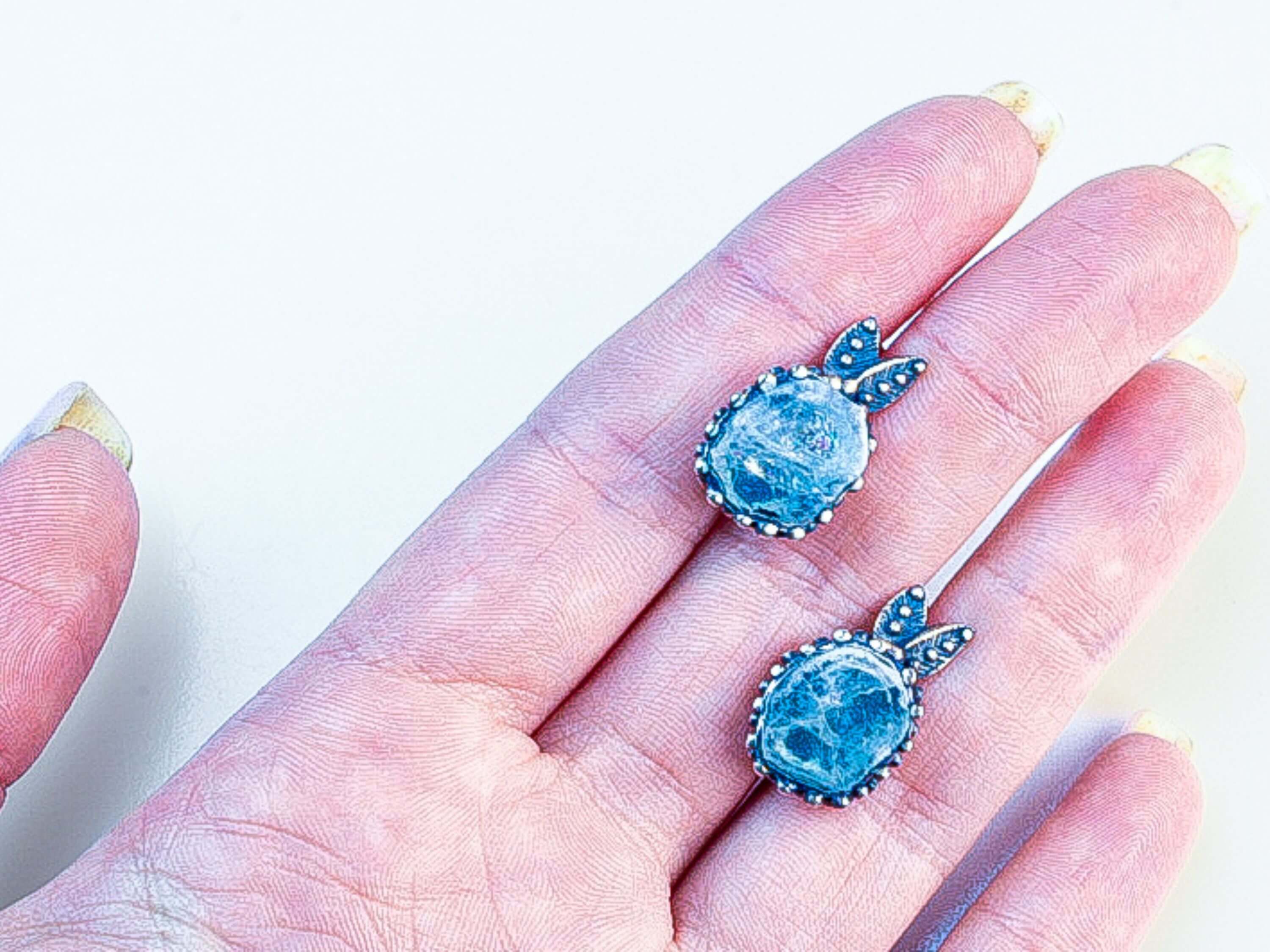 A pair of handcrafted aquamarine earrings held in hand to demonstrate scale and craftsmanship