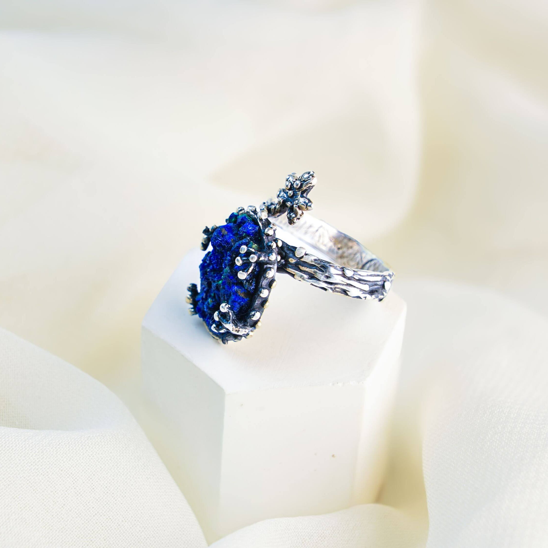 Handmade bohemian lapis lazuli jewelry displayed on a minimalist white aesthetic pedestal