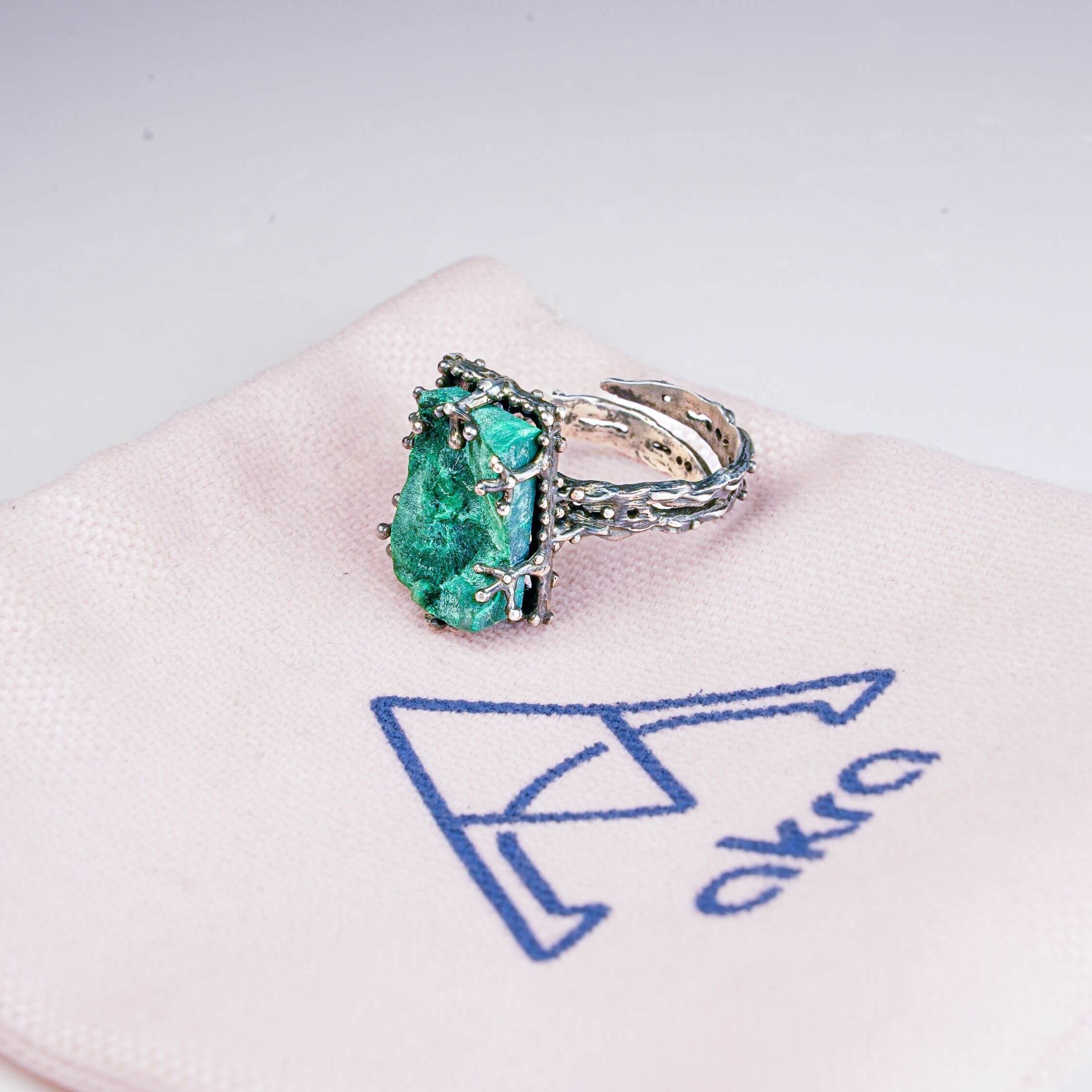 Handcrafted gemstone jewelry presentation with malachite ring on branded Akra jewelry pouch