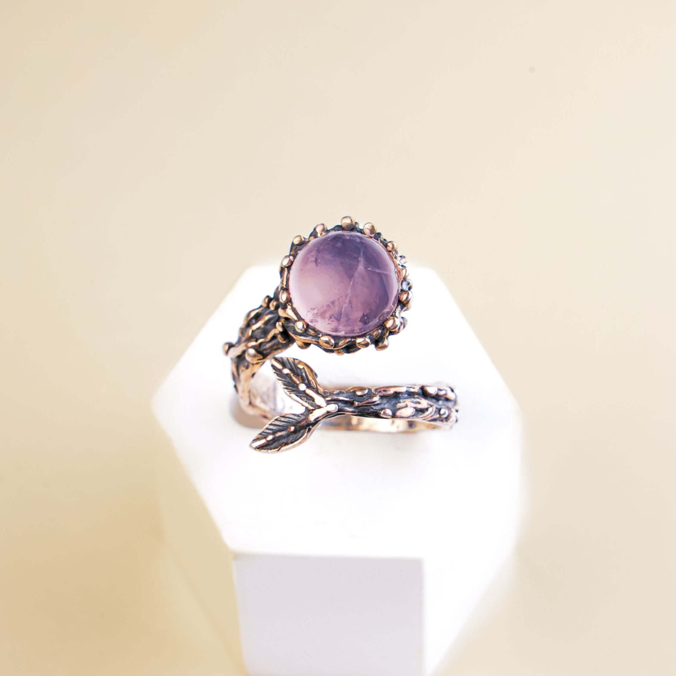 Frontal view of a light pink rose quartz ring highlighting the artistic silver leaf accents