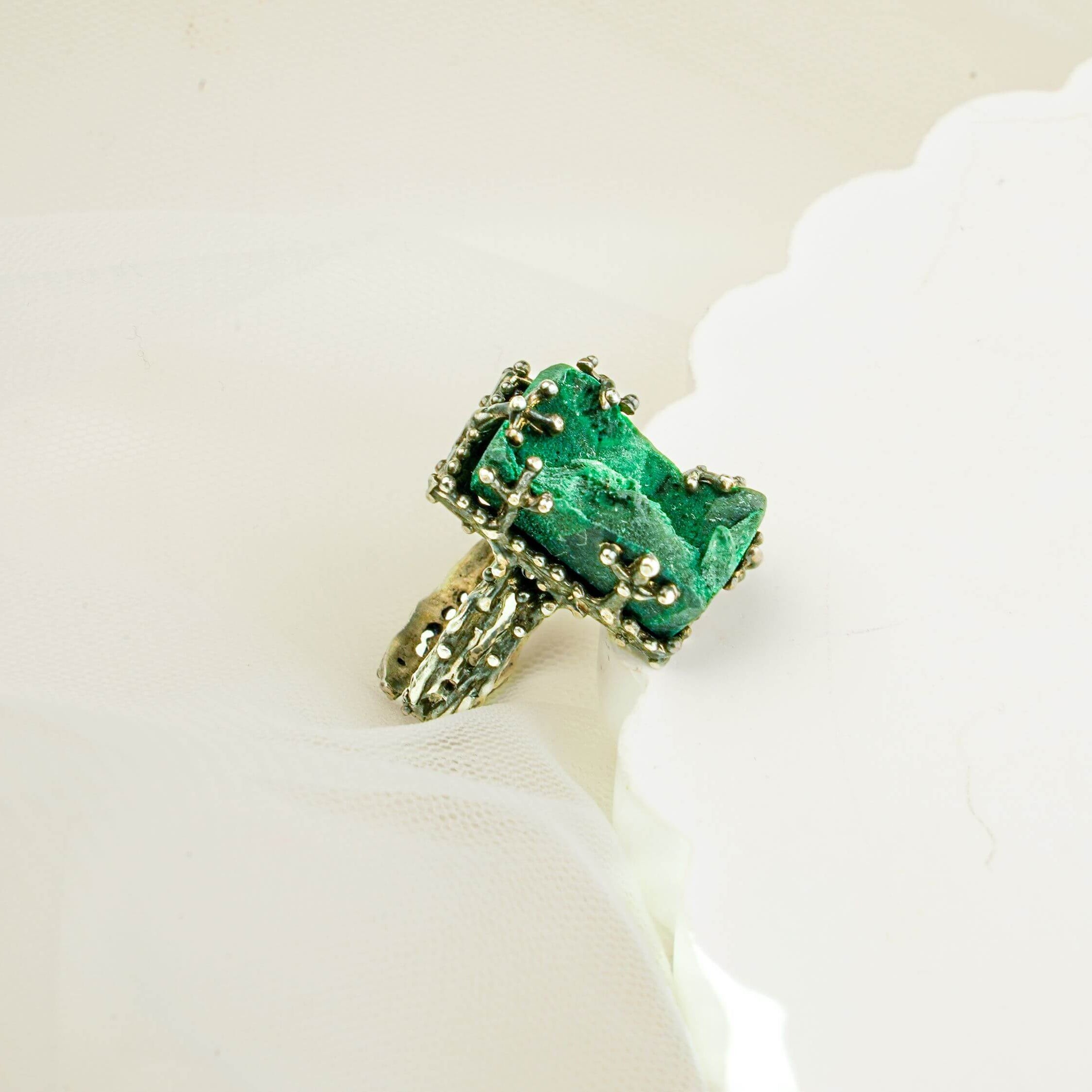 High-angle shot of a rectangular emerald green malachite ring on a white decorative platform