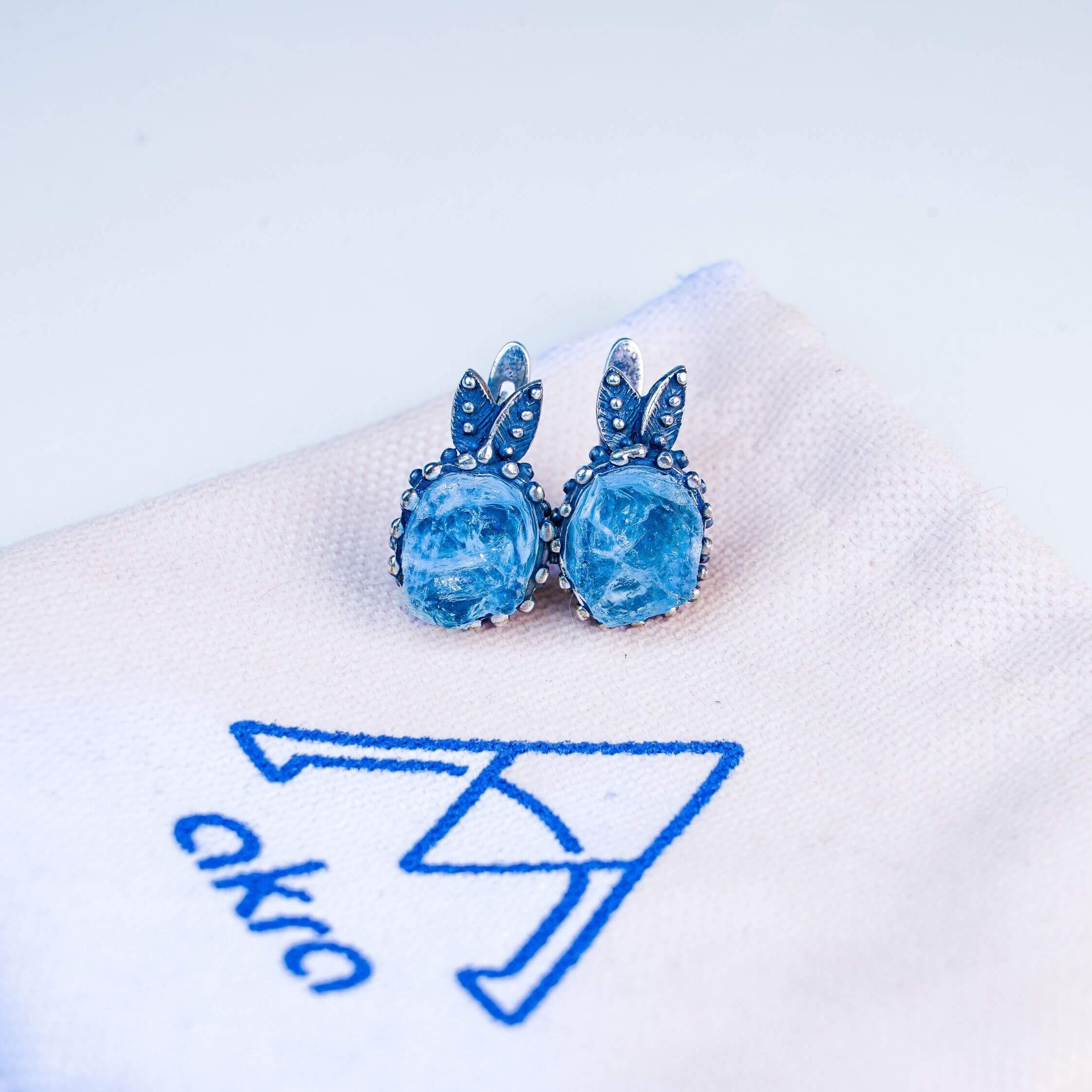 Aesthetic presentation of aquamarine jewelry on a branded Akra fabric jewelry pouch