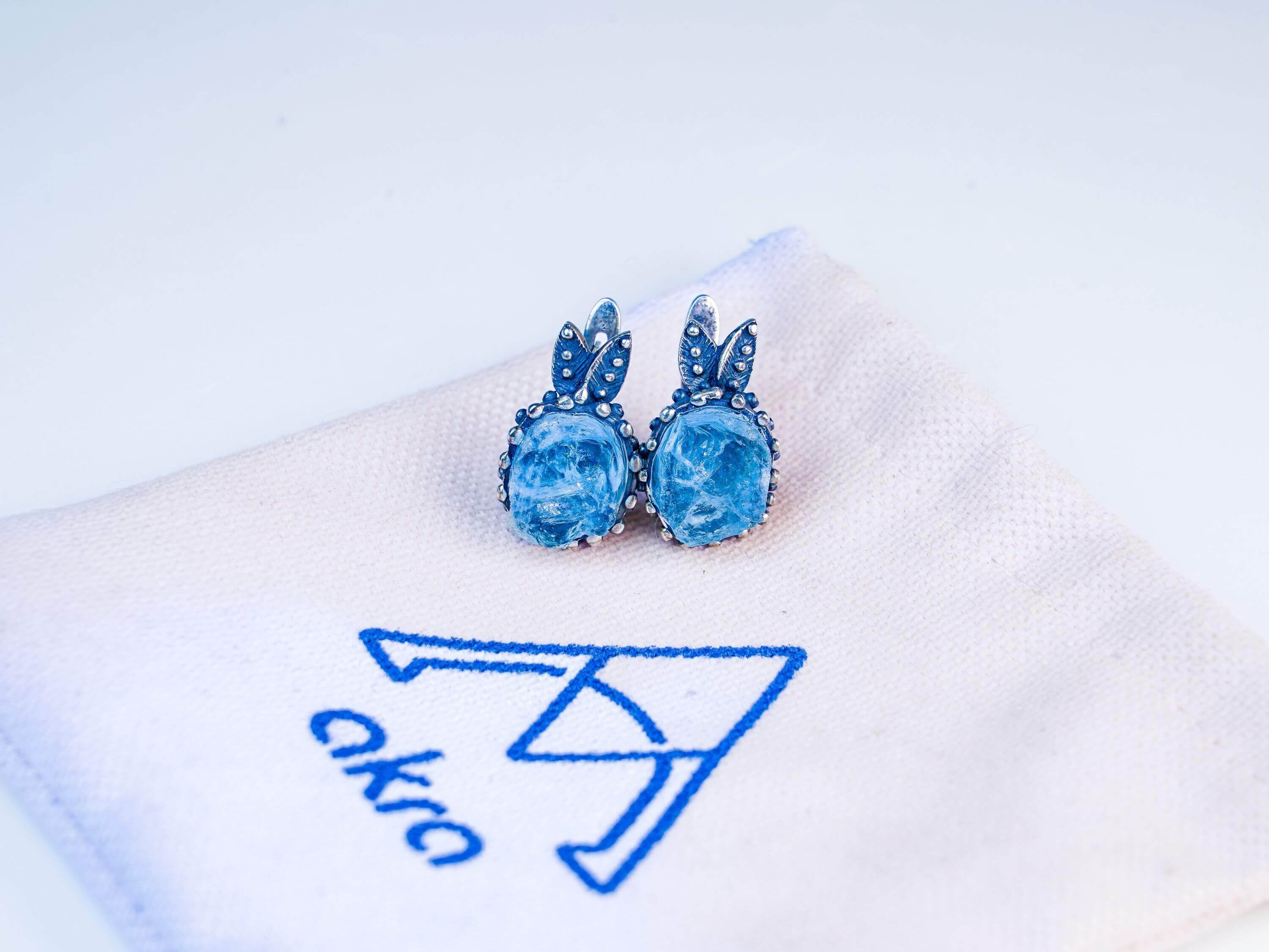 Aesthetic presentation of aquamarine jewelry on a branded Akra fabric jewelry pouch