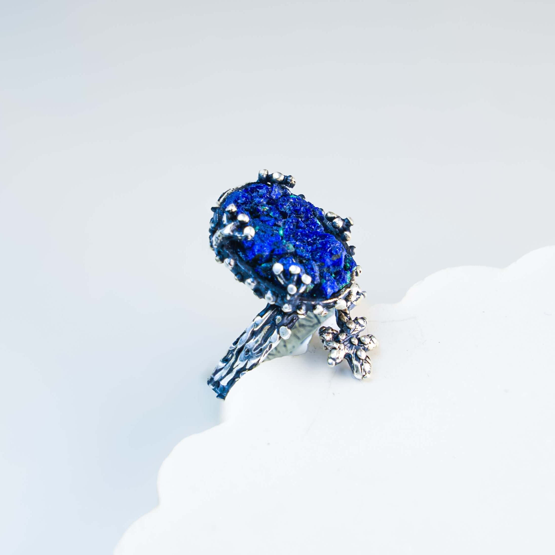 High-angle shot of the iridescent blue lapis lazuli ring on a branded Akra jewelry pouch