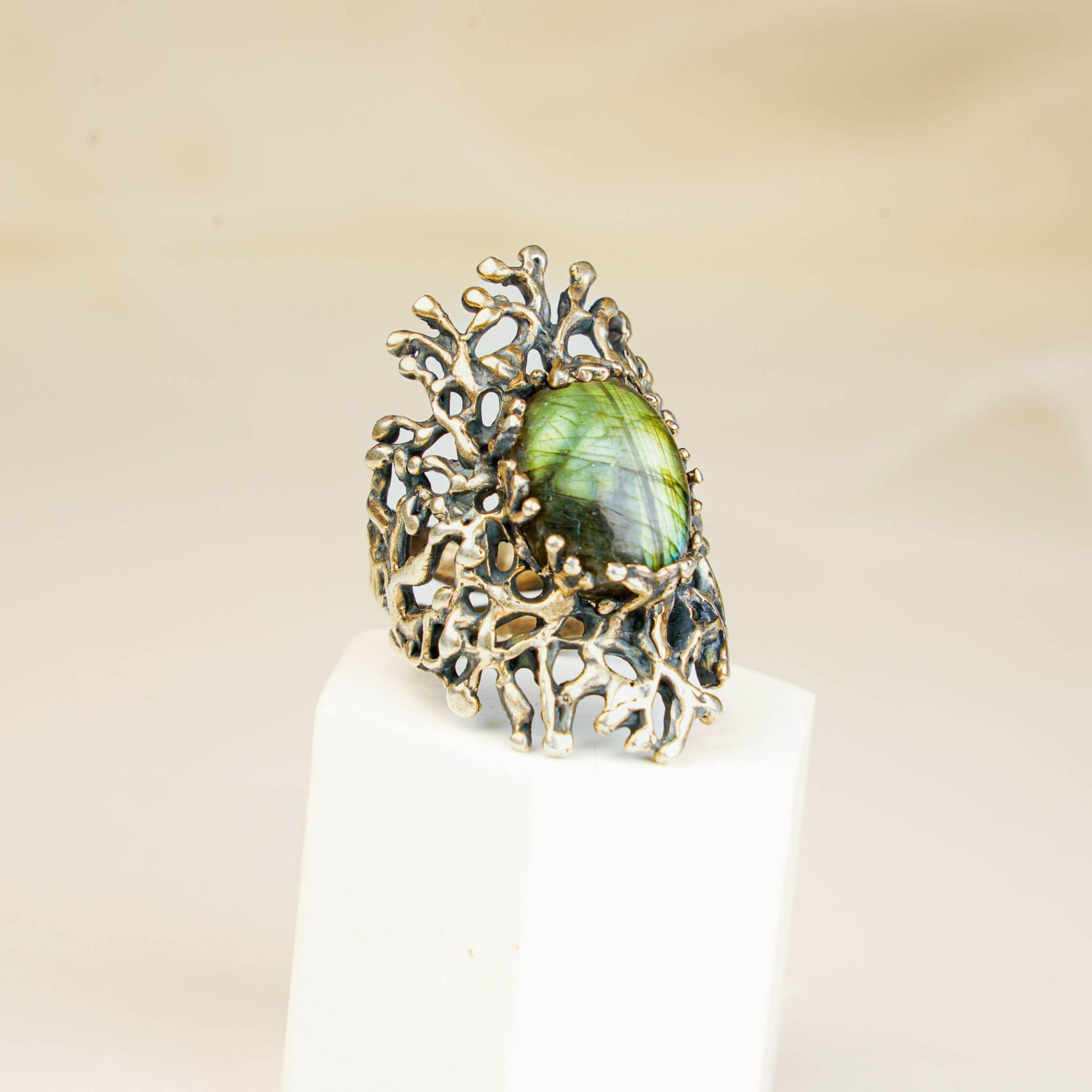 Vertical shot of a handcrafted gothic style silver ring with a glowing green labradorite