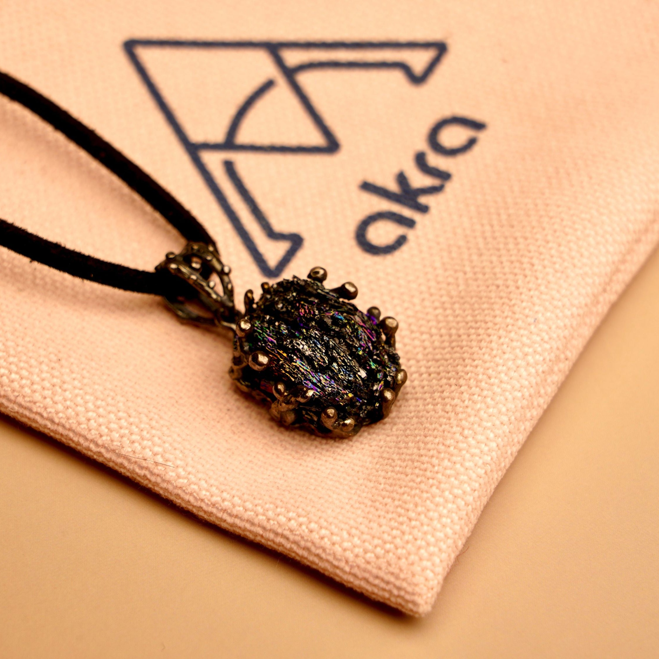 Obsidian black crystal pendant resting on a branded AKRA jewelry pouch, ideal for safe storage or gifting