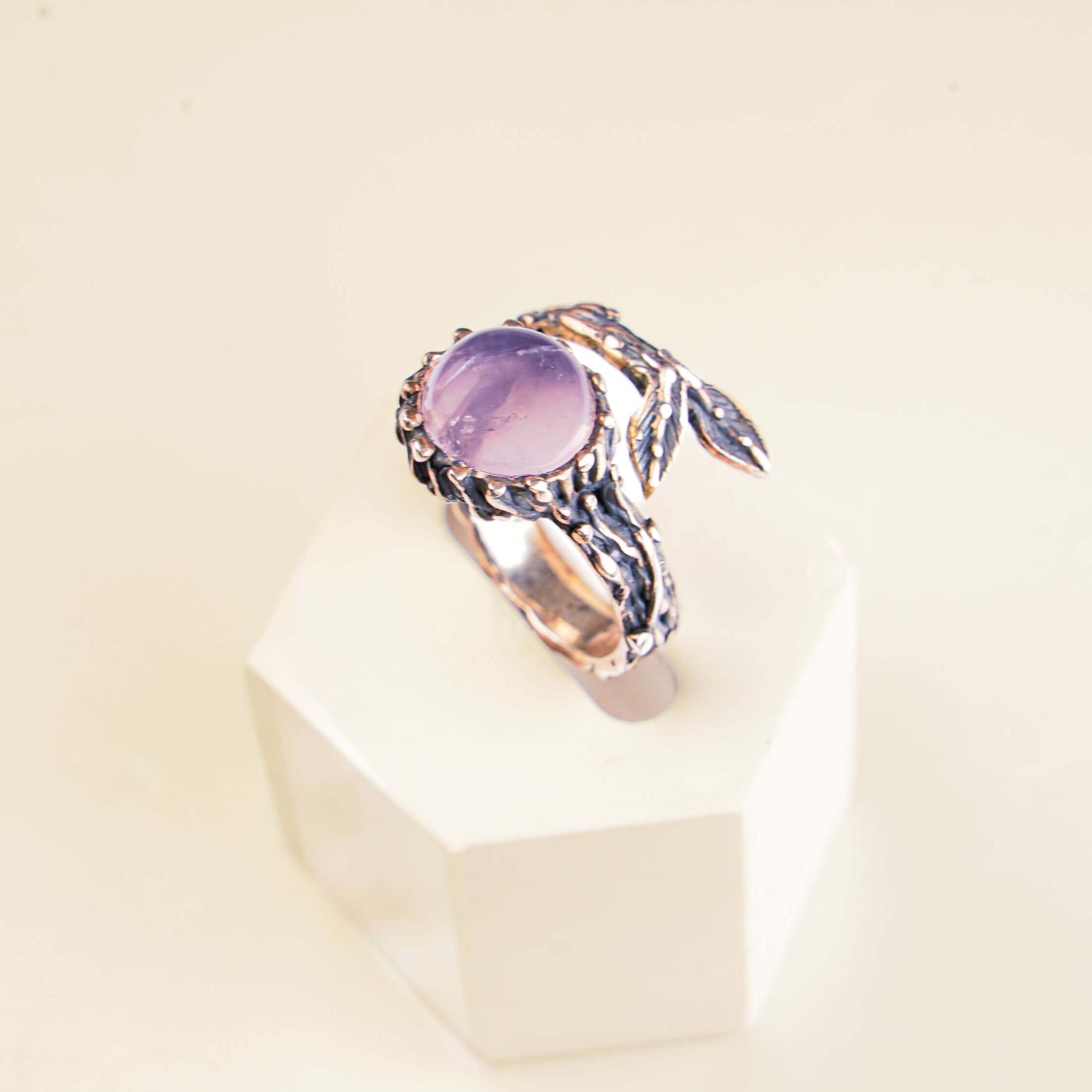 Top-down aesthetic shot of a natural rose quartz ring on a clean, modern background.