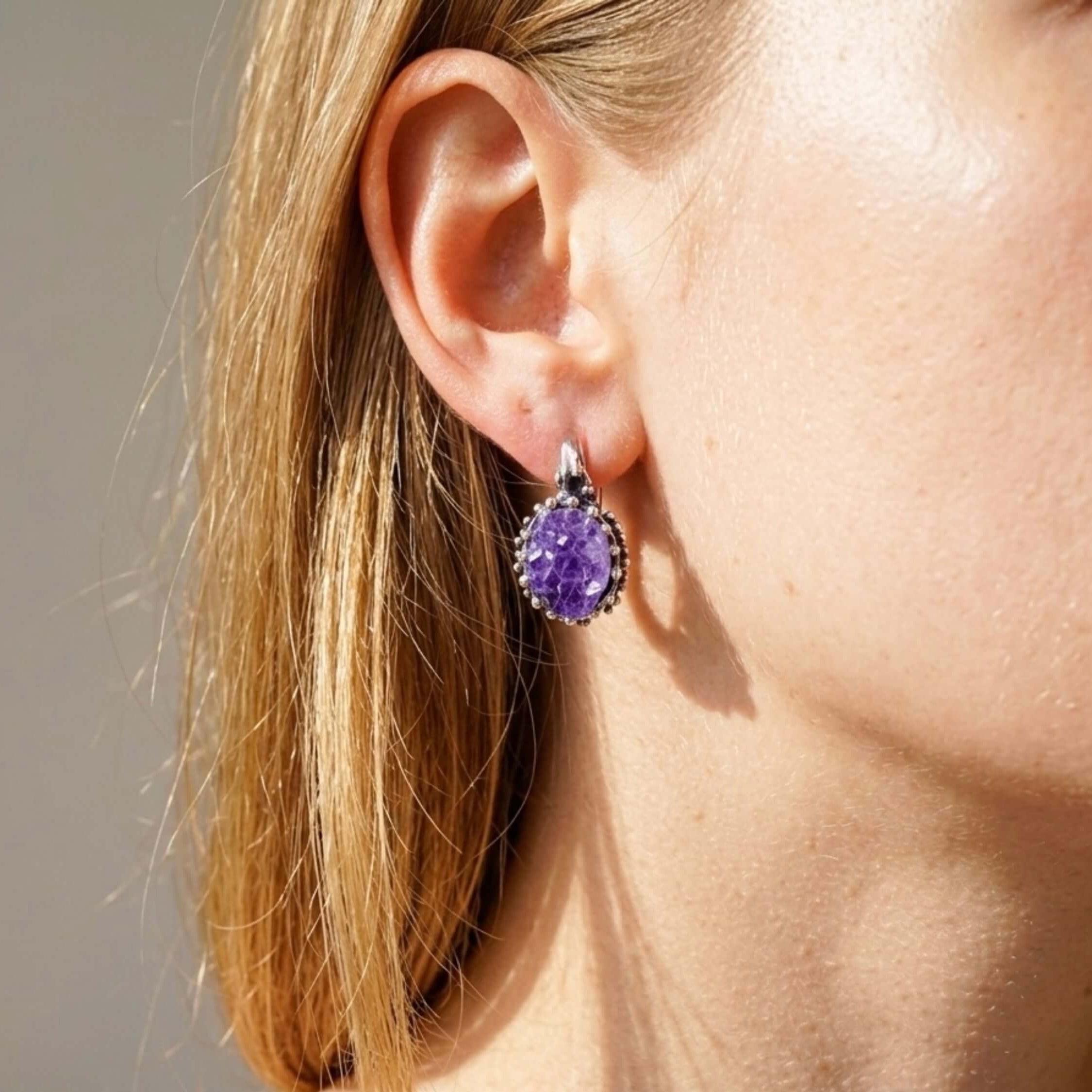 Model wearing Akra Gems raw amethyst earrings, showing the elegant oval drop and vibrant purple crystal color