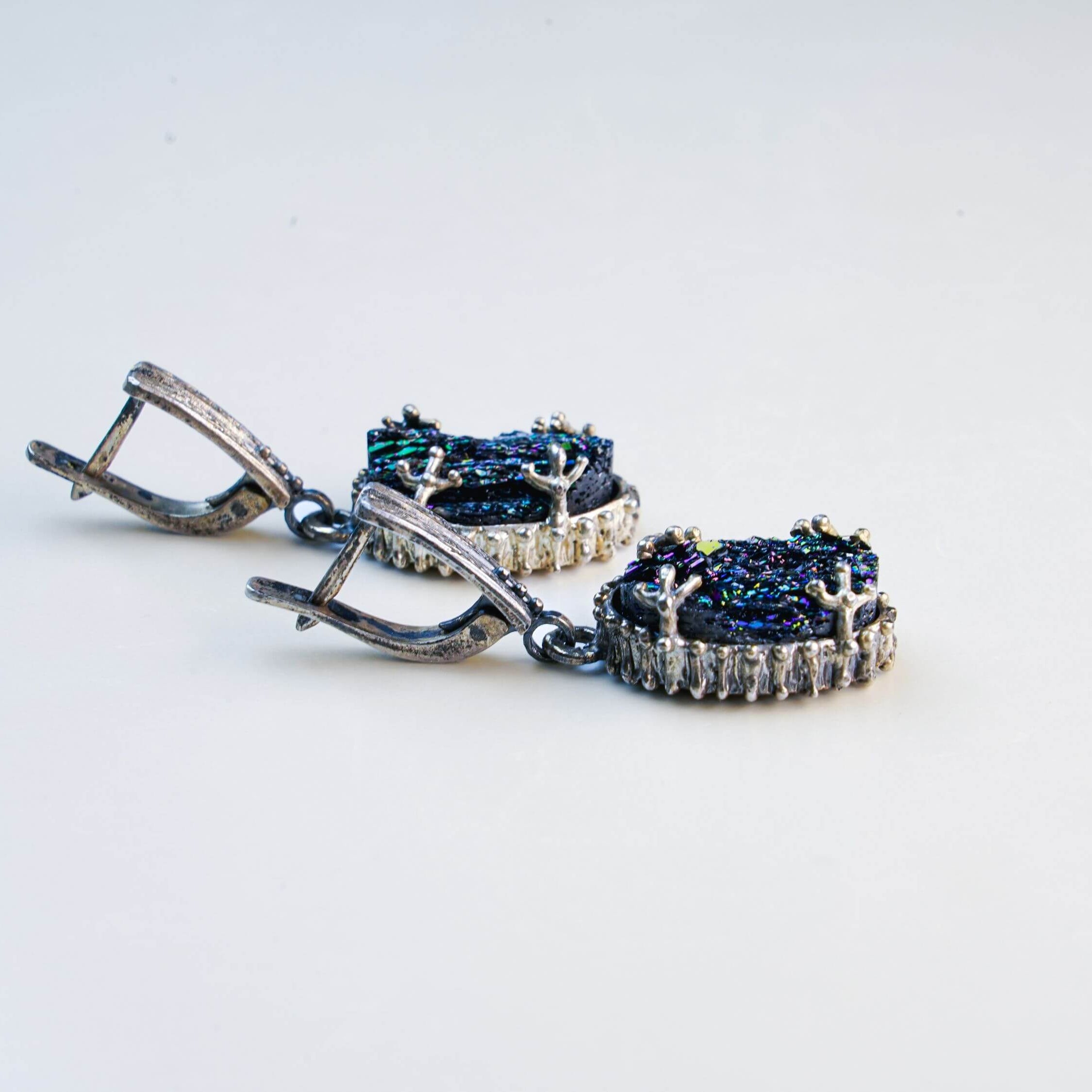Side-angle view of the earrings under soft light, highlighting the depth of the raw crystal and the ornate silver detailing