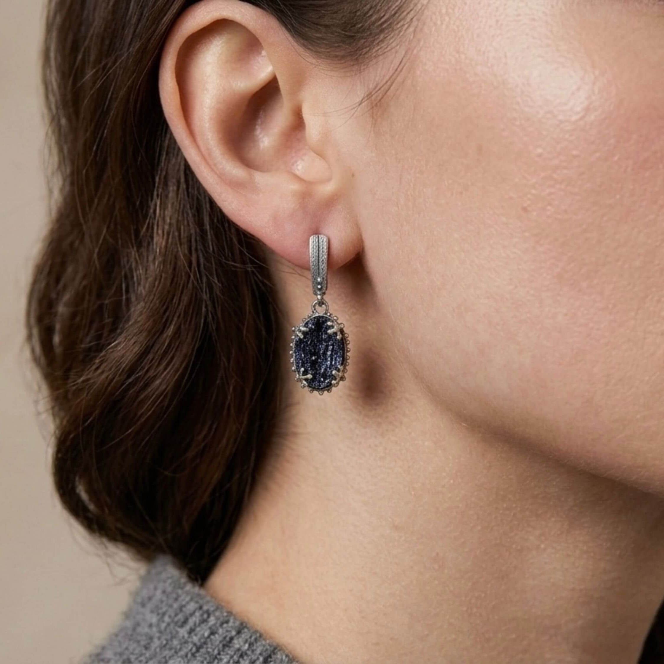 A model wearing Akra Gems raw black tourmaline earrings, showing how the bold oval shape and dark gemstone complement an elegant look