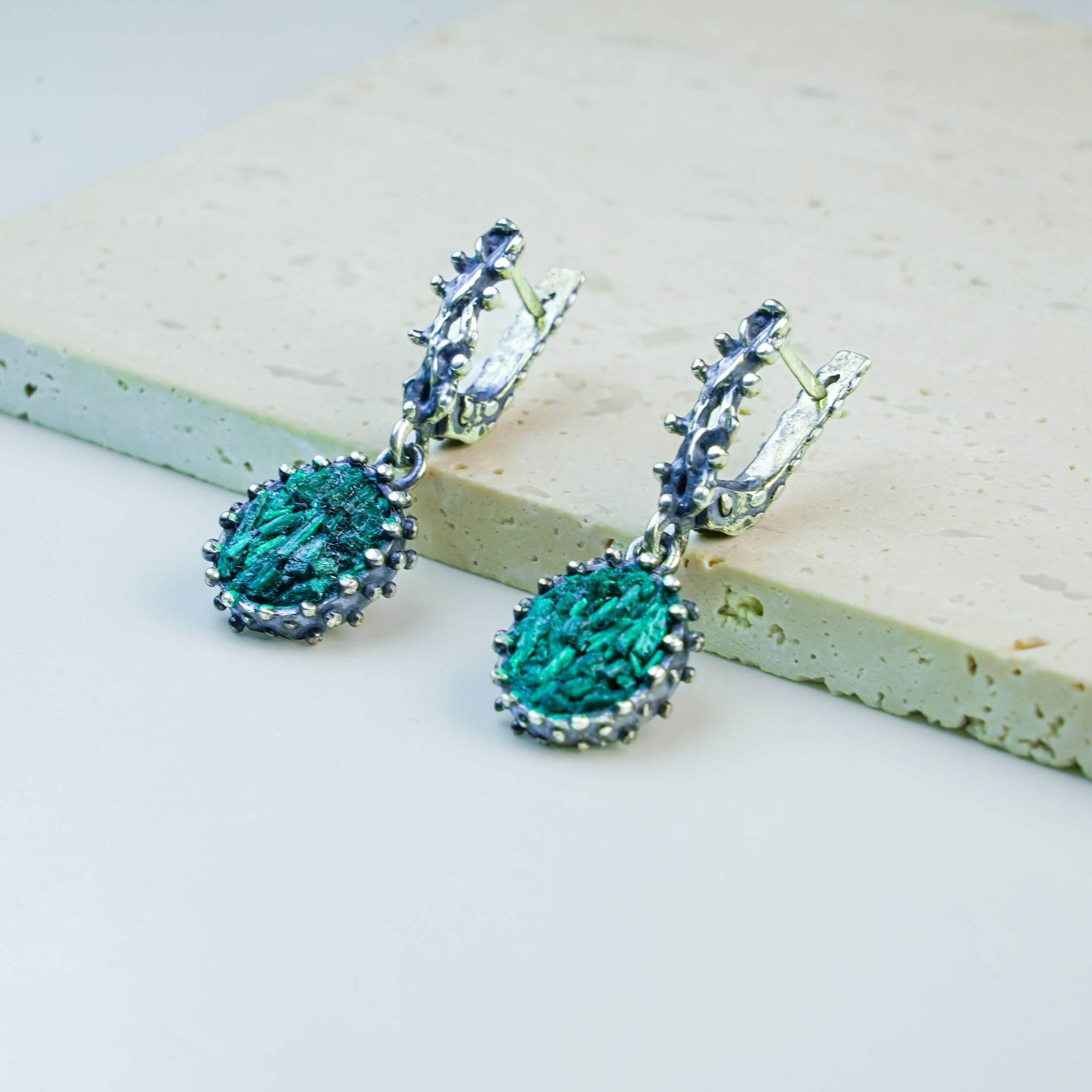 A direct front view of both Malachite drop earrings, emphasizing the symmetry, the detailed silver frames, and the bold green stone colors