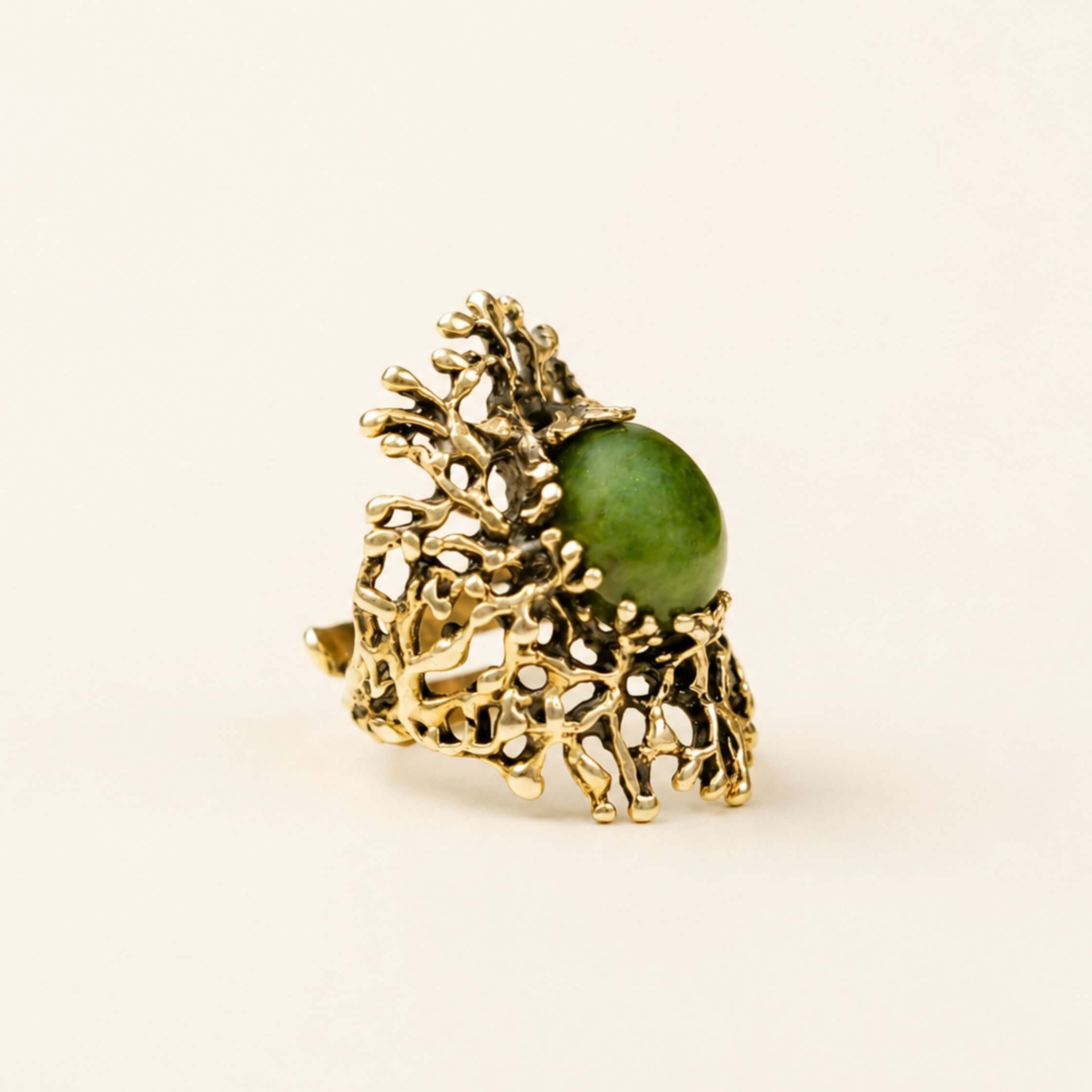 A massive green Jade statement ring featuring an intricate, organic sterling silver setting, displayed on a minimalist background.