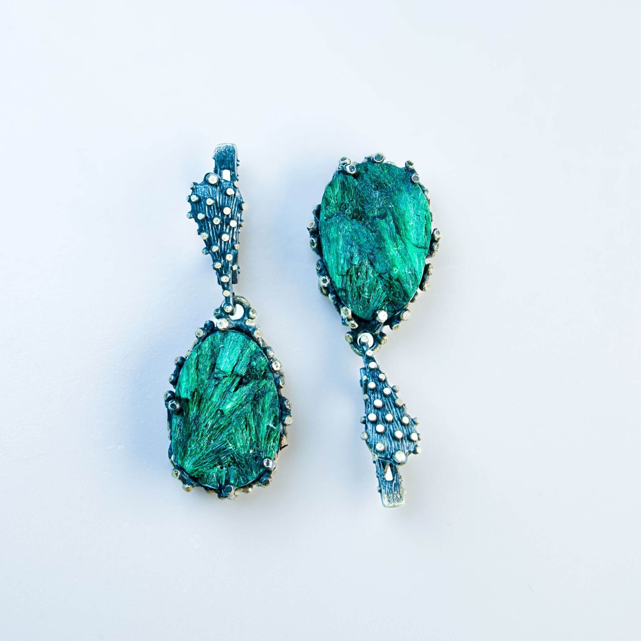 Direct front-facing view of the pear-shaped earrings, emphasizing the symmetry and the rich texture of the silver setting