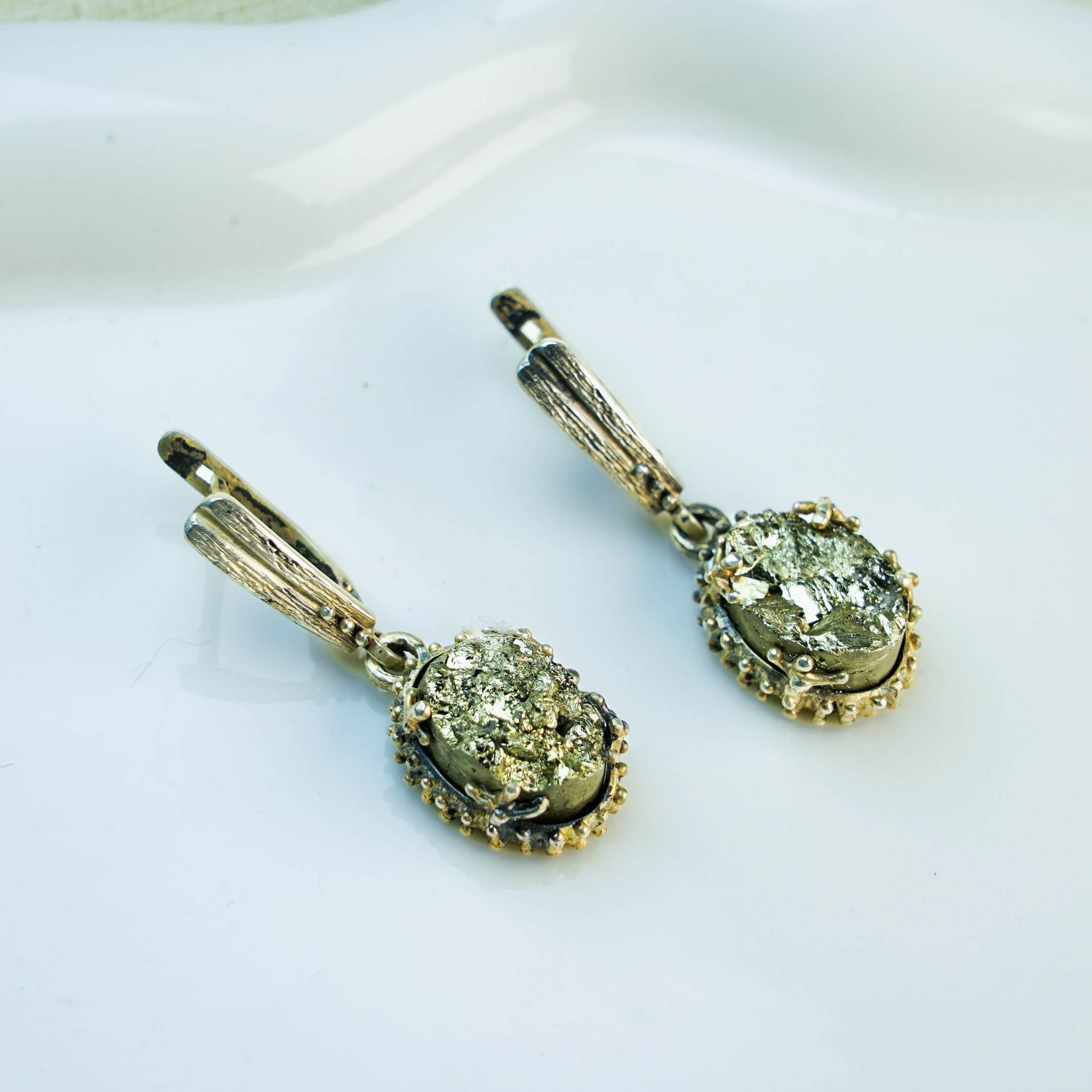 Direct front-facing view of both pyrite dangles, emphasizing the symmetry and the contrast between the silver and the gold-tone stone