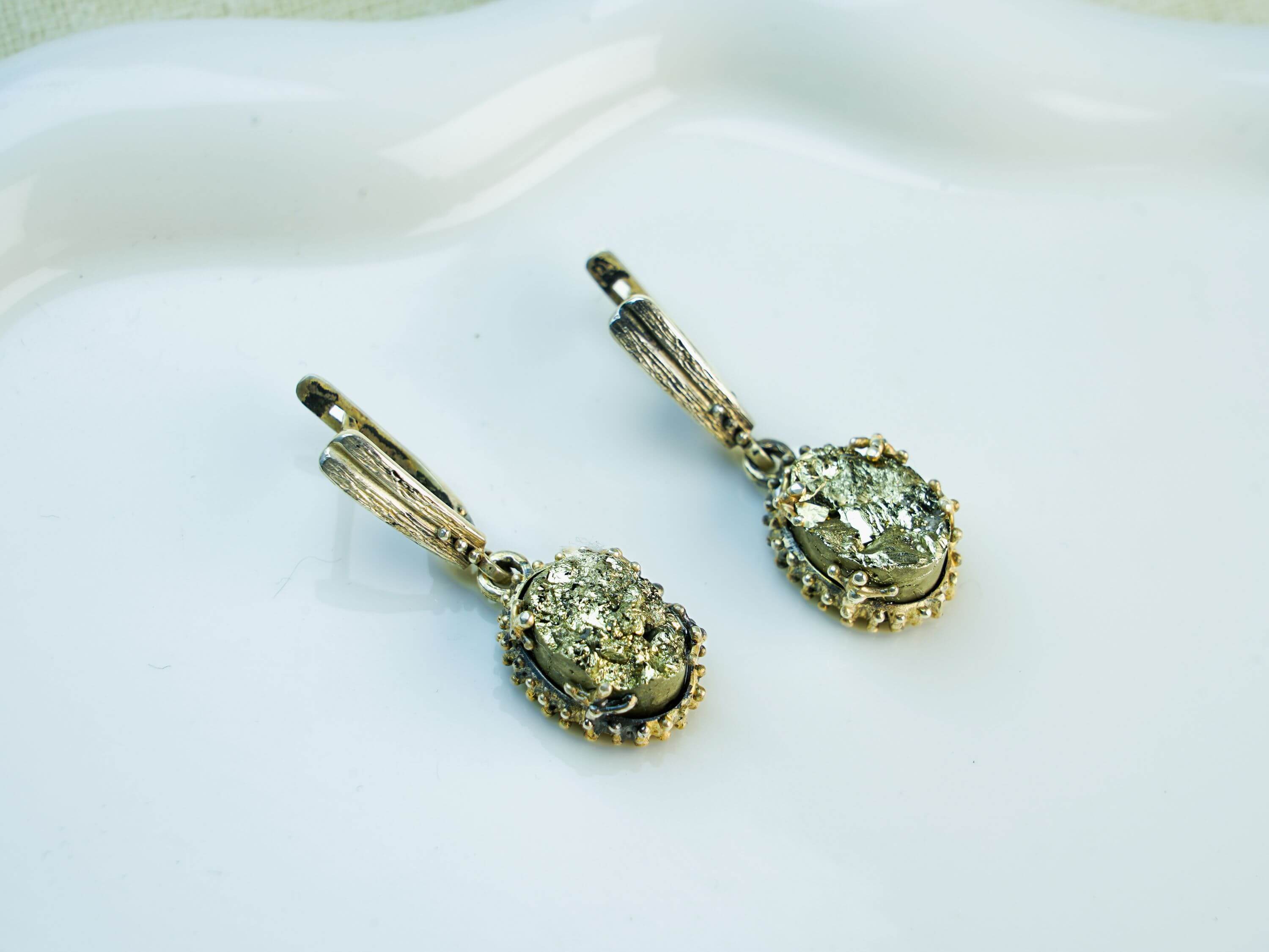Direct front-facing view of both pyrite dangles, emphasizing the symmetry and the contrast between the silver and the gold-tone stone