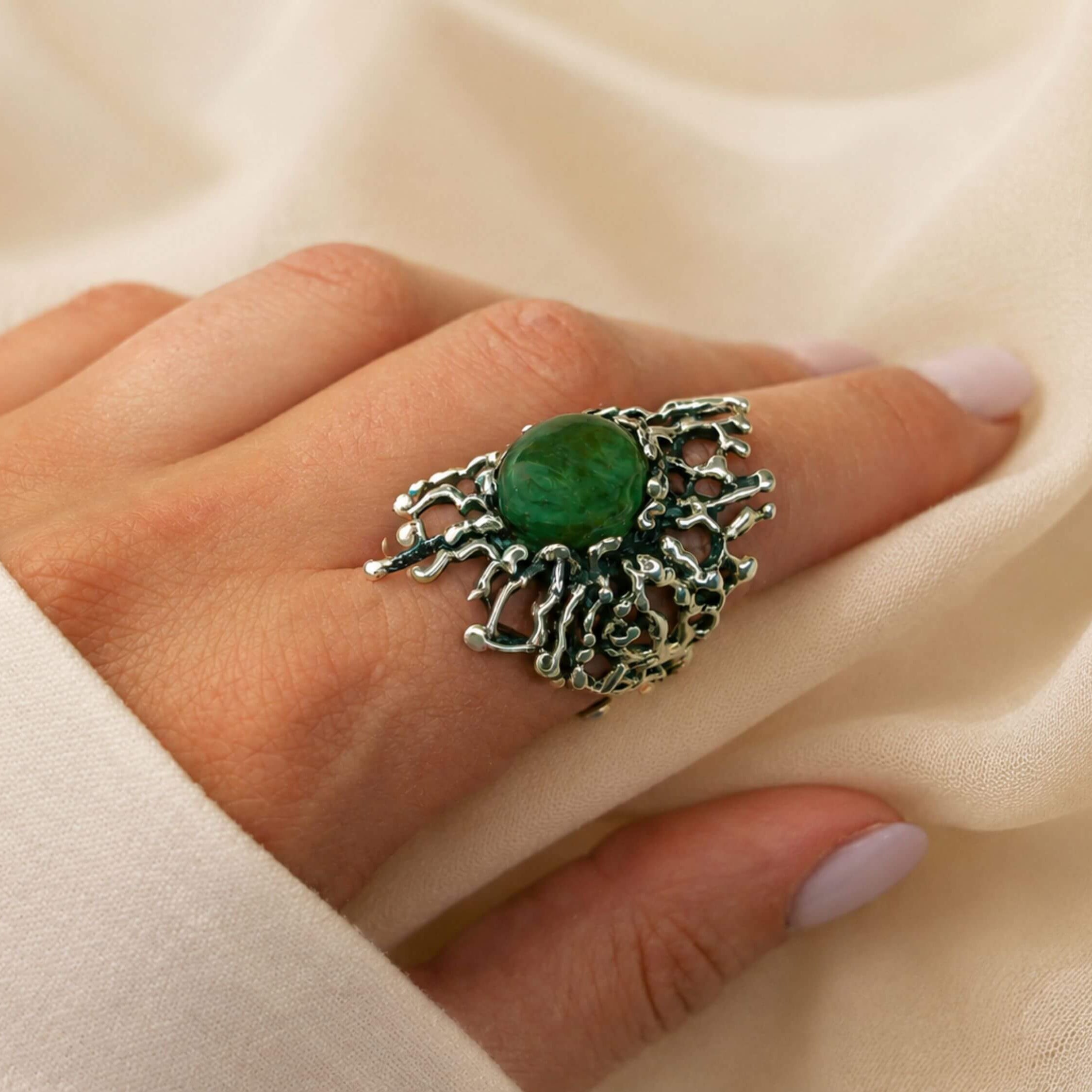 A model wearing the bold Akra Gems Jade ring, showcasing its impressive scale and the vibrant green color of the gemstone on a finger.