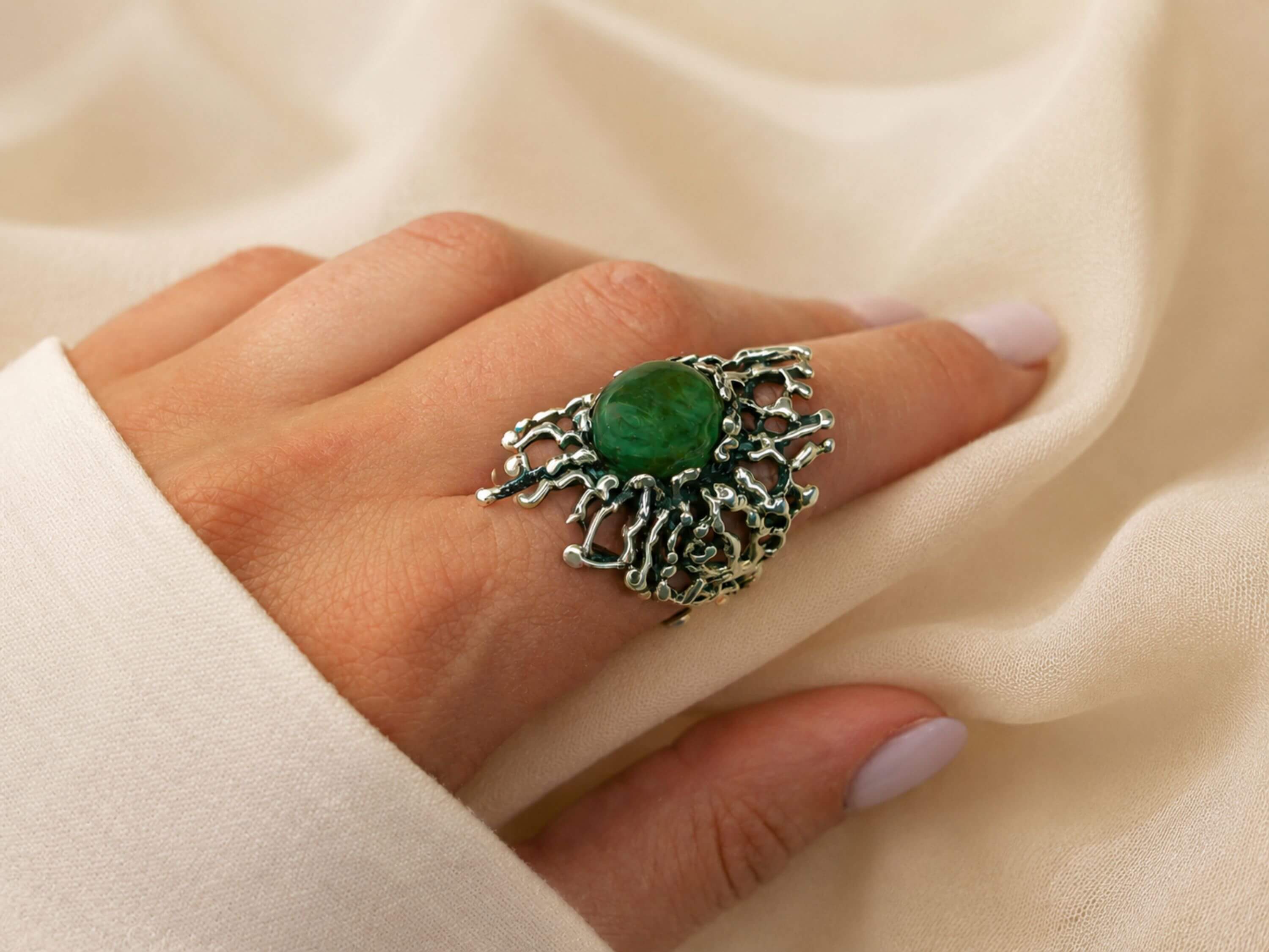 A model wearing the bold Akra Gems Jade ring, showcasing its impressive scale and the vibrant green color of the gemstone on a finger.