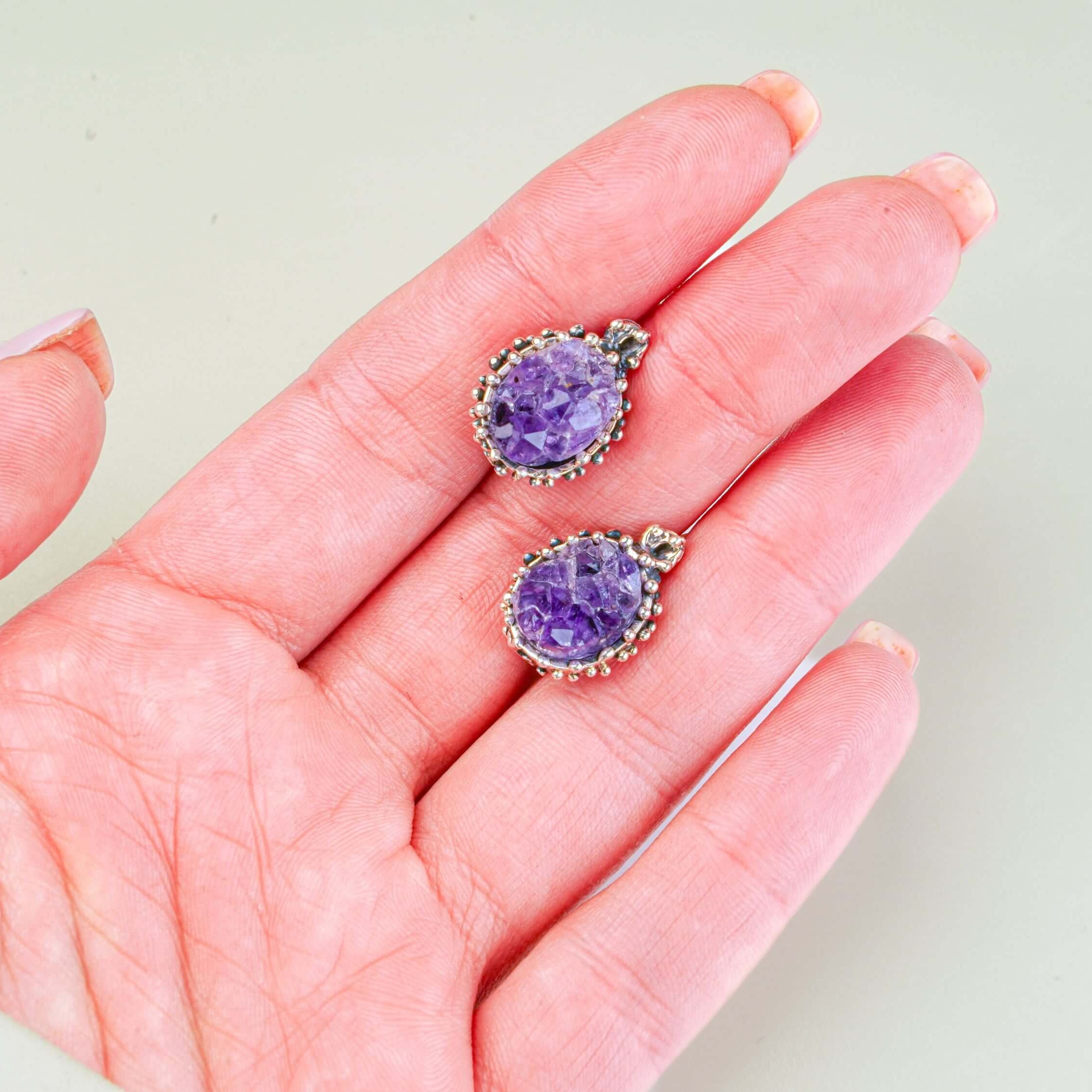 Handheld shot of both amethyst dangles, demonstrating the bold statement size and handcrafted silver frame