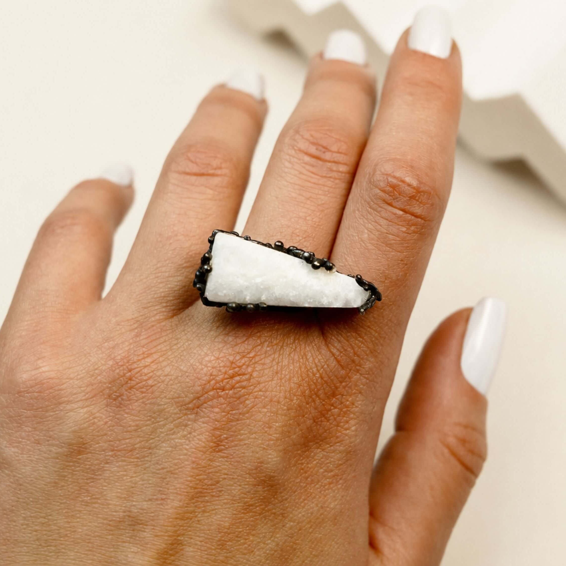 A model wearing the large raw Moonstone ring, showcasing the striking contrast between the white stone and the hand-textured dark silver band.