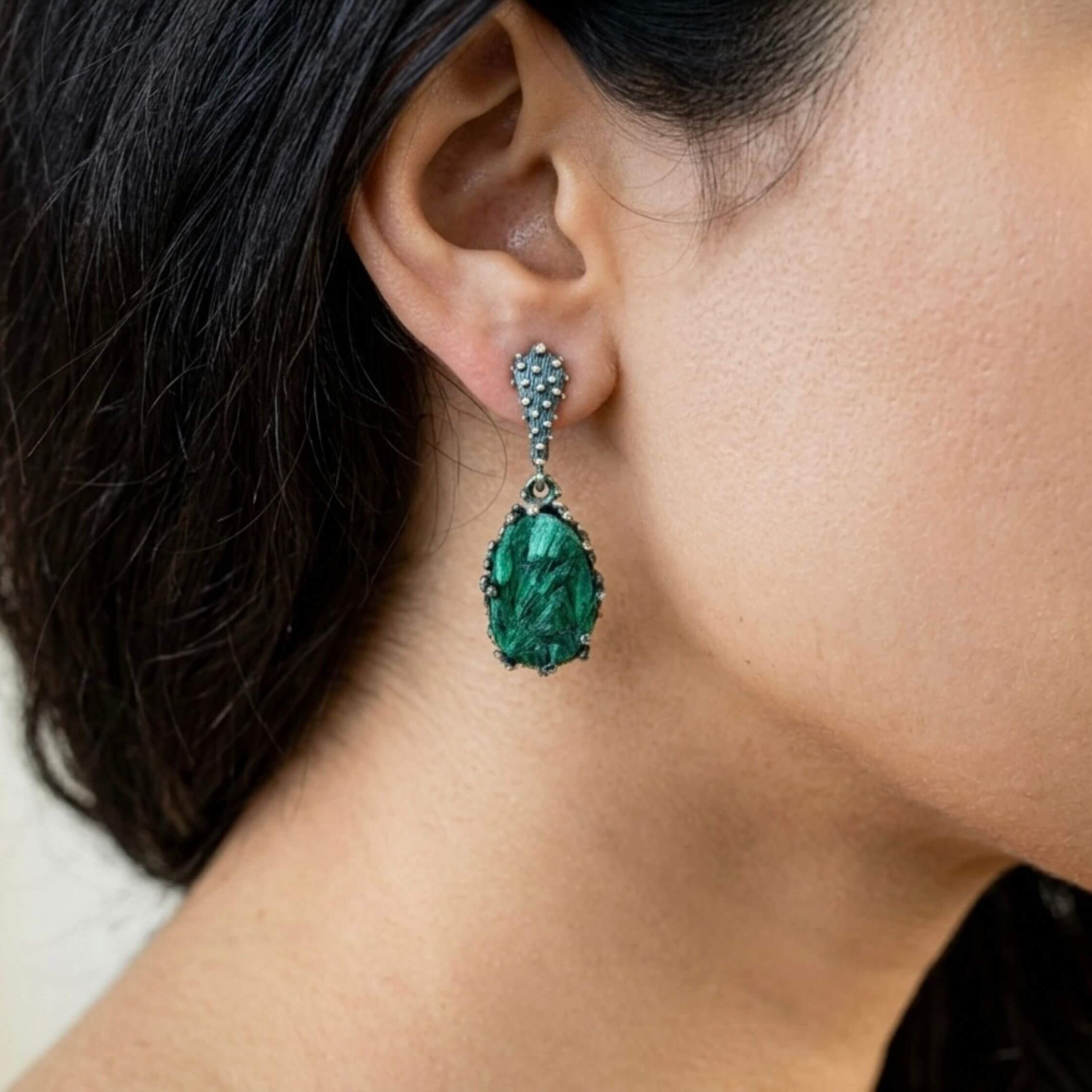 Model wearing pear-shaped Akra Gems malachite earrings, showing the elegant drop length and vibrant green color