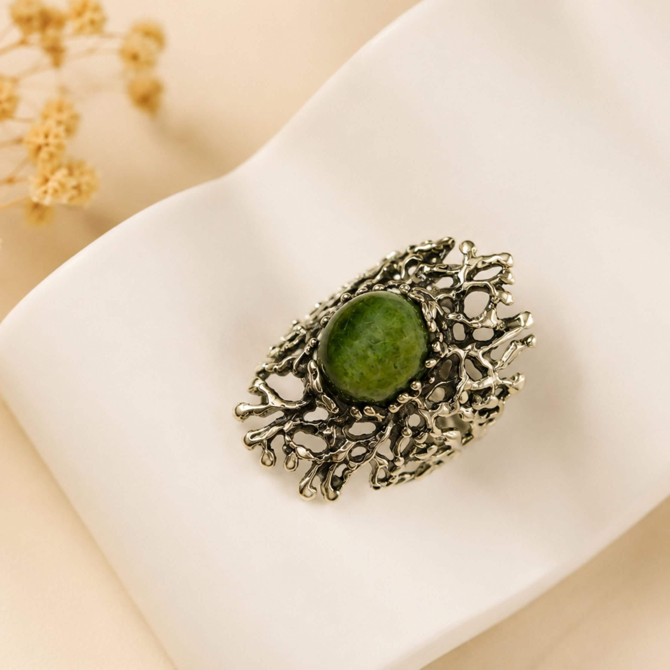Close-up shot of the natural green Jade stone, highlighting the polished surface and the unique, branch-like sterling silver metalwork.