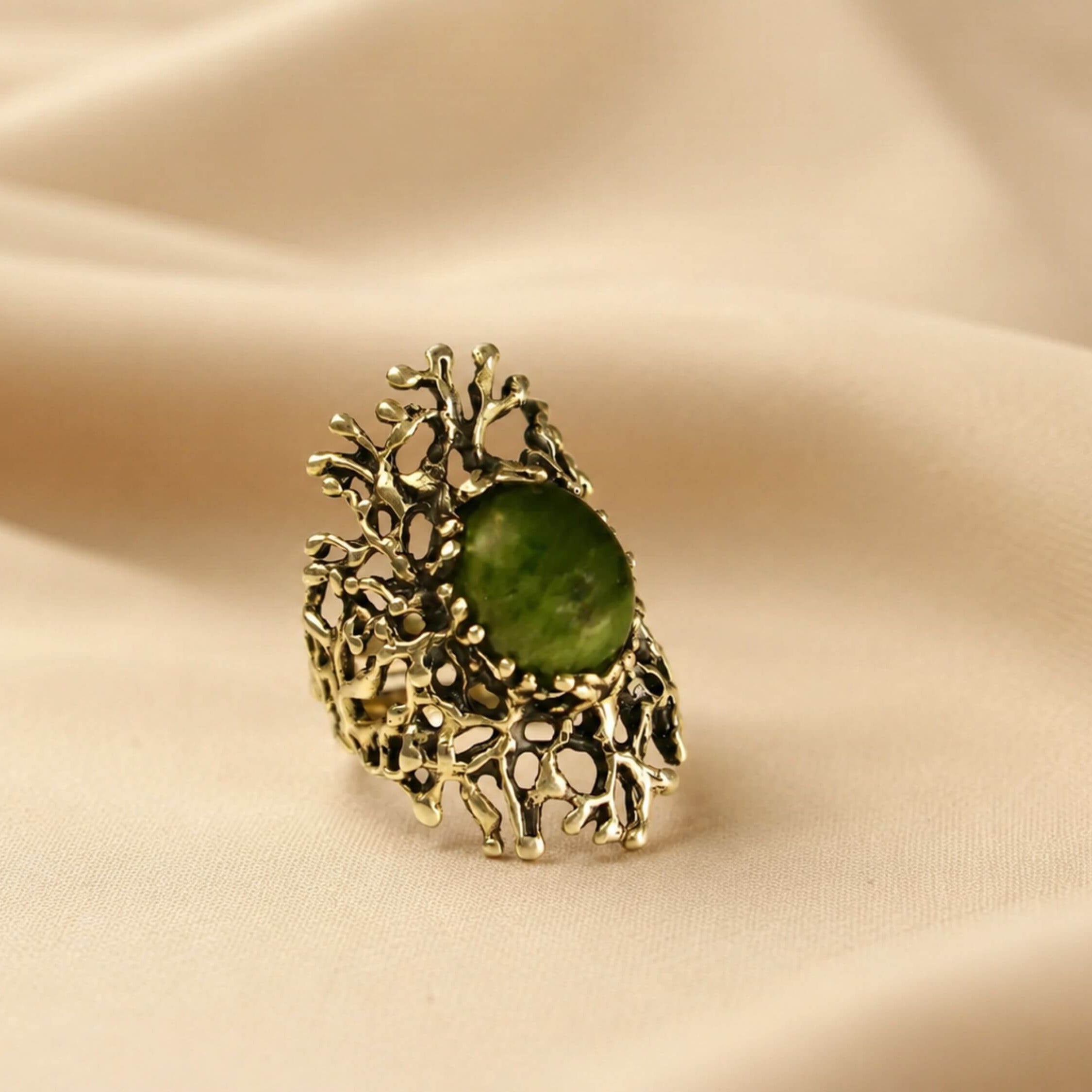 Artistic shot of the Jade ring on a soft fabric background, capturing its earthy and sophisticated nature-inspired design.