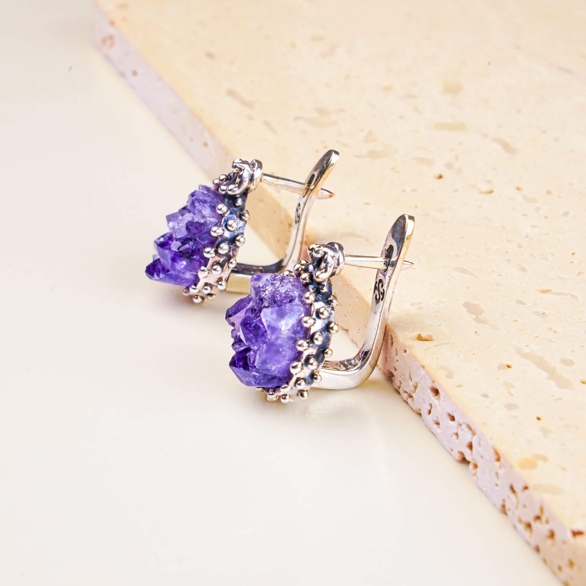 Oval Raw Amethyst earrings featuring natural purple crystals in a detailed sterling silver frame, shot on a clean background