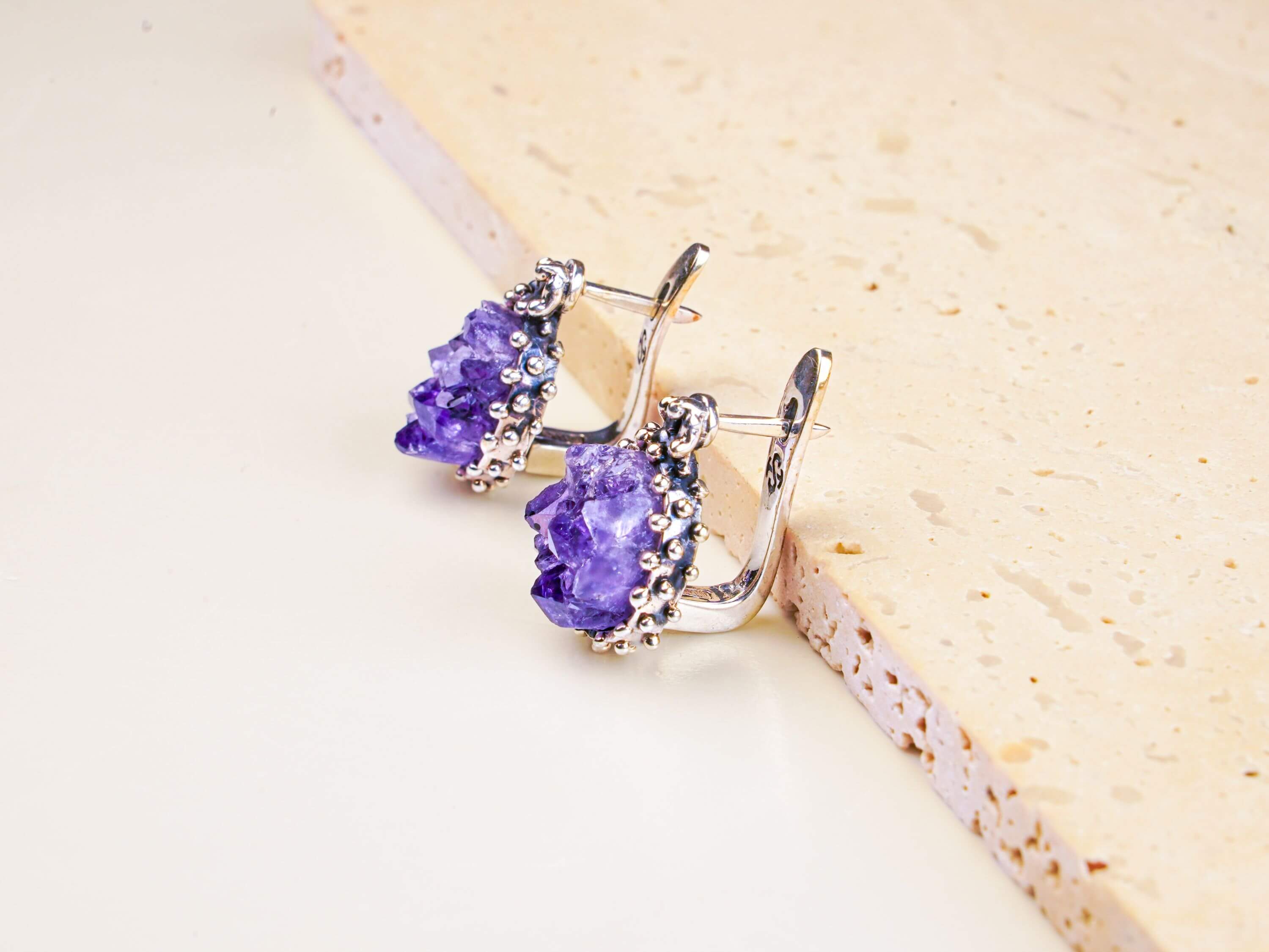 Oval Raw Amethyst earrings featuring natural purple crystals in a detailed sterling silver frame, shot on a clean background