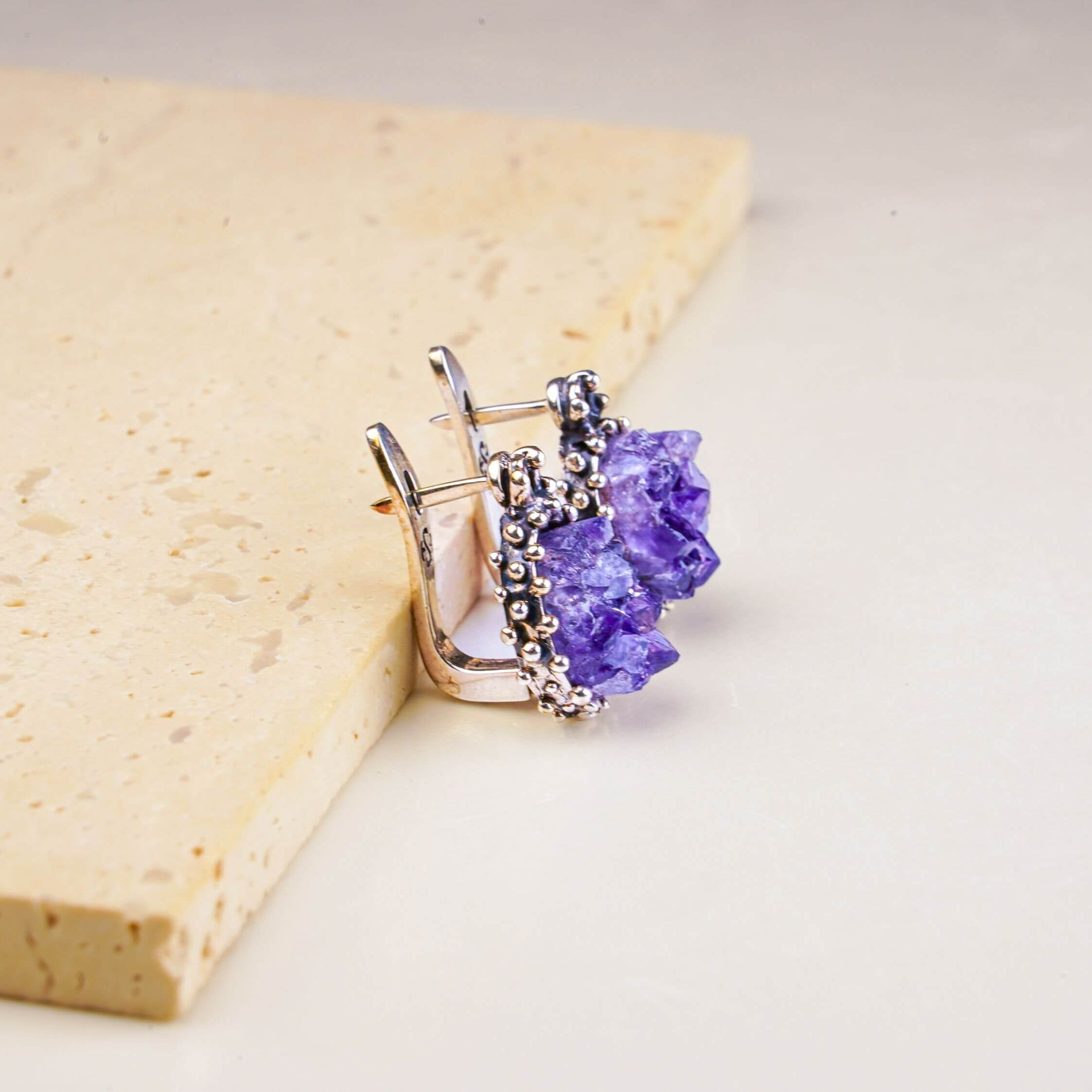 Side profile of the oval amethyst dangles, showing the depth of the raw crystal and the ornate silver setting