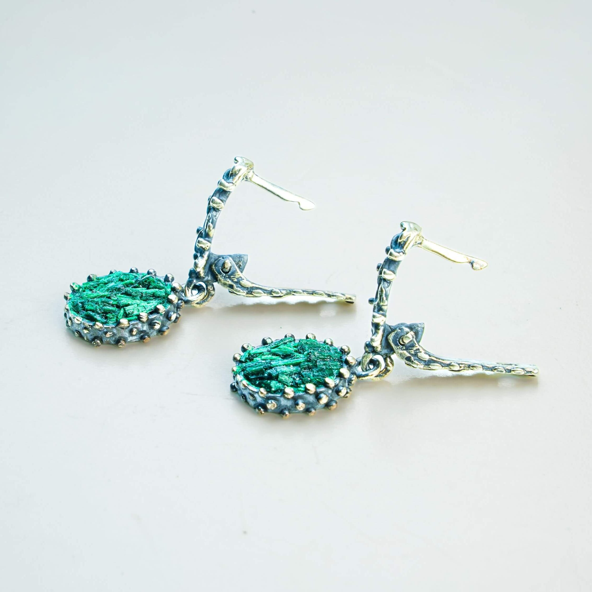 Detailed shot of the Malachite gemstone under soft light, capturing the natural luster and unique stone banding reflections