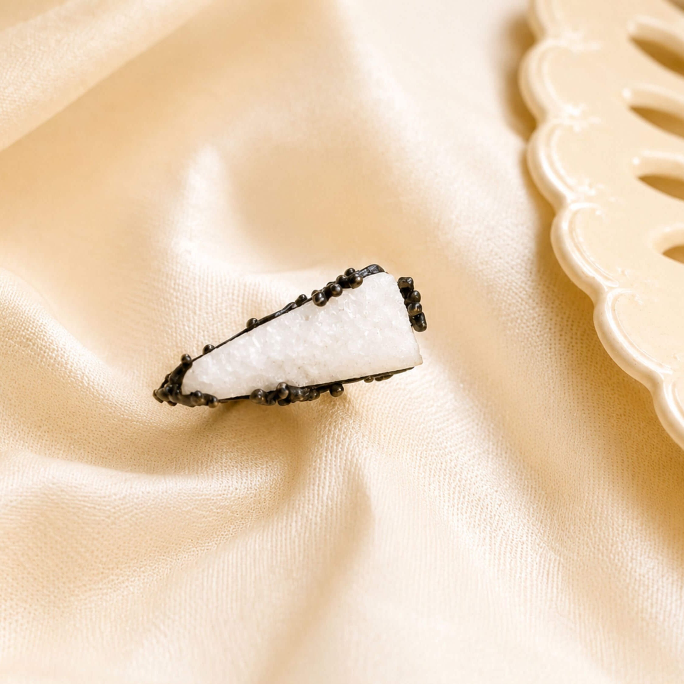 A top-down view of the white Moonstone ring on a soft silk-like background, emphasizing its sophisticated and earthy design.