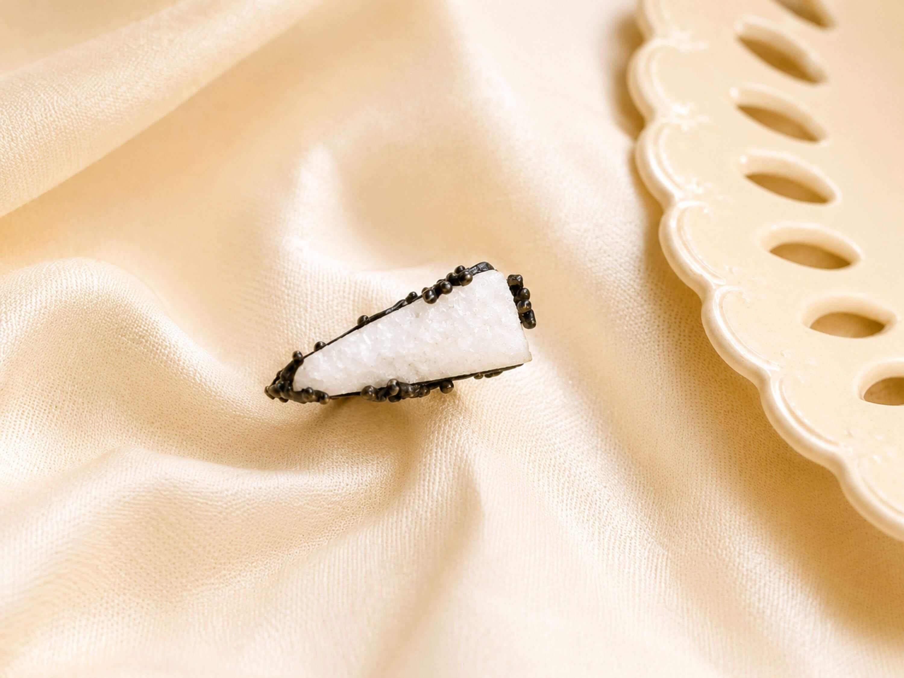 A top-down view of the white Moonstone ring on a soft silk-like background, emphasizing its sophisticated and earthy design.