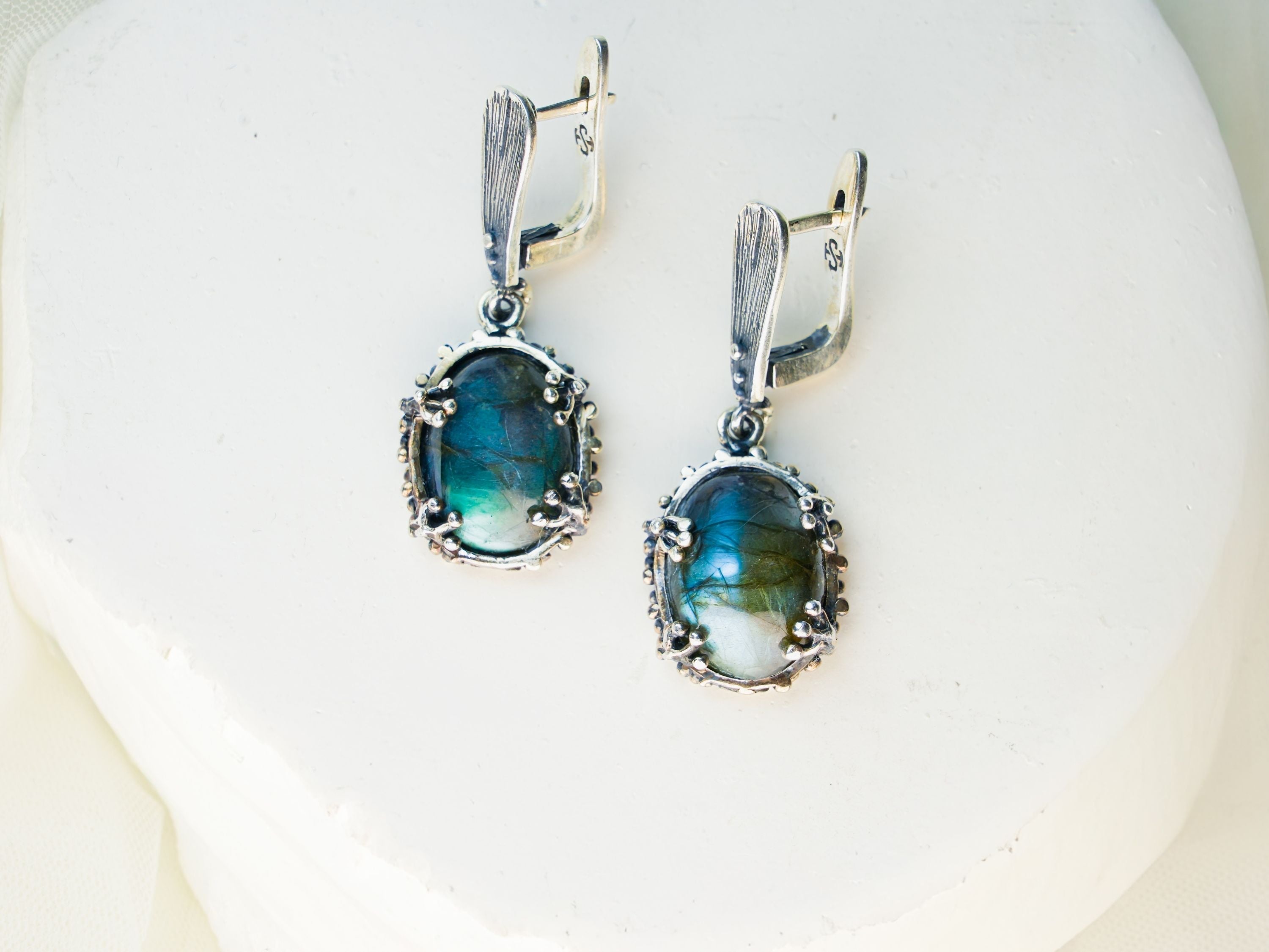 Handcrafted sterling silver earrings with iridescent blue-flash labradorite gemstones, featured in AKRA's guide to magical stones.