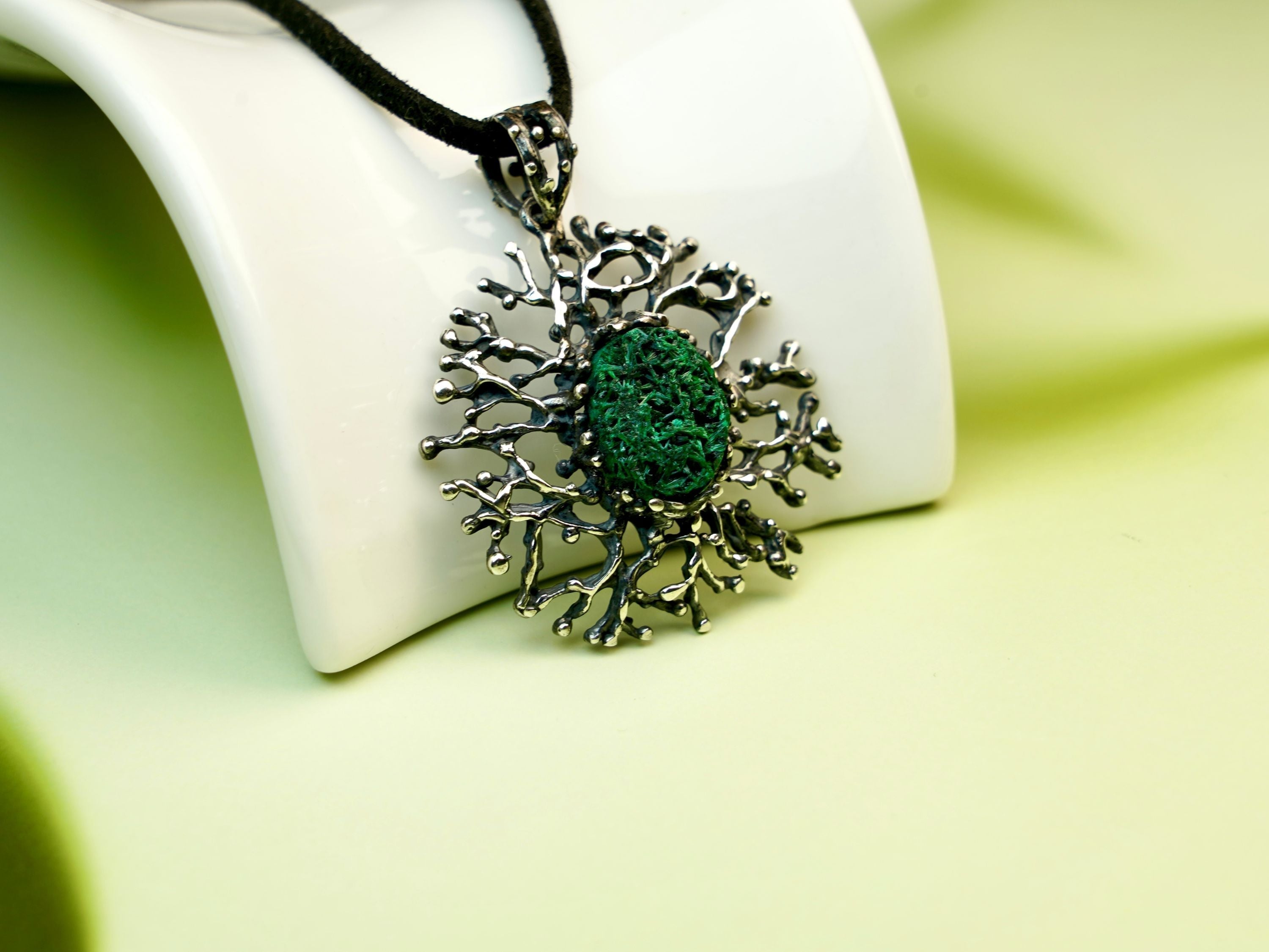 Handcrafted malachite pendant by AKRA, inspired by forest magic and Georgian craftsmanship, featuring a raw green gemstone in a sterling silver coral-style setting.