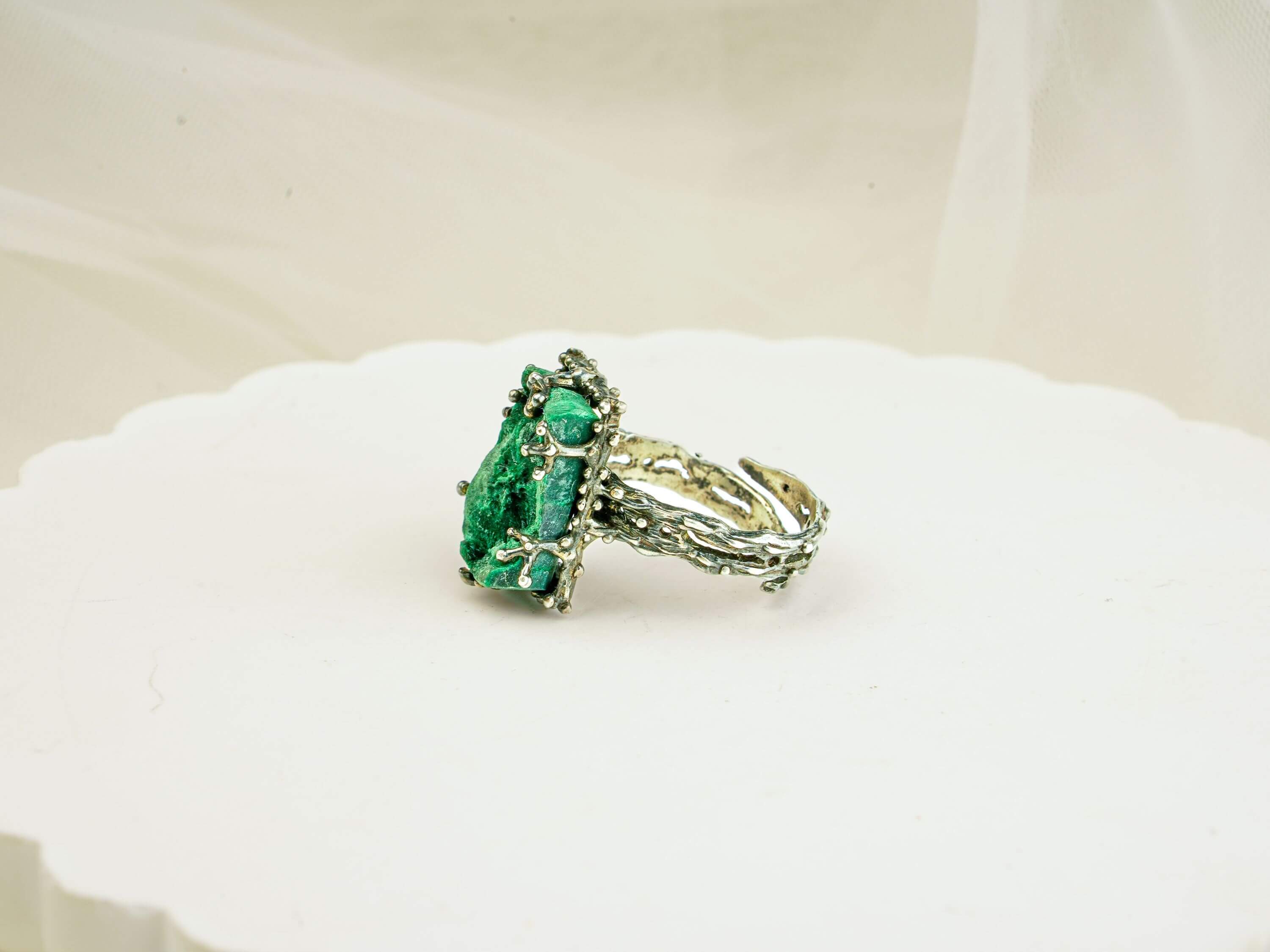 Bohemian style silver malachite ring displayed on a white aesthetic pedestal