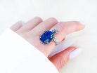 Statement lapis lazuli ring worn on finger showing the rich blue stone and nature-inspired silver wrap