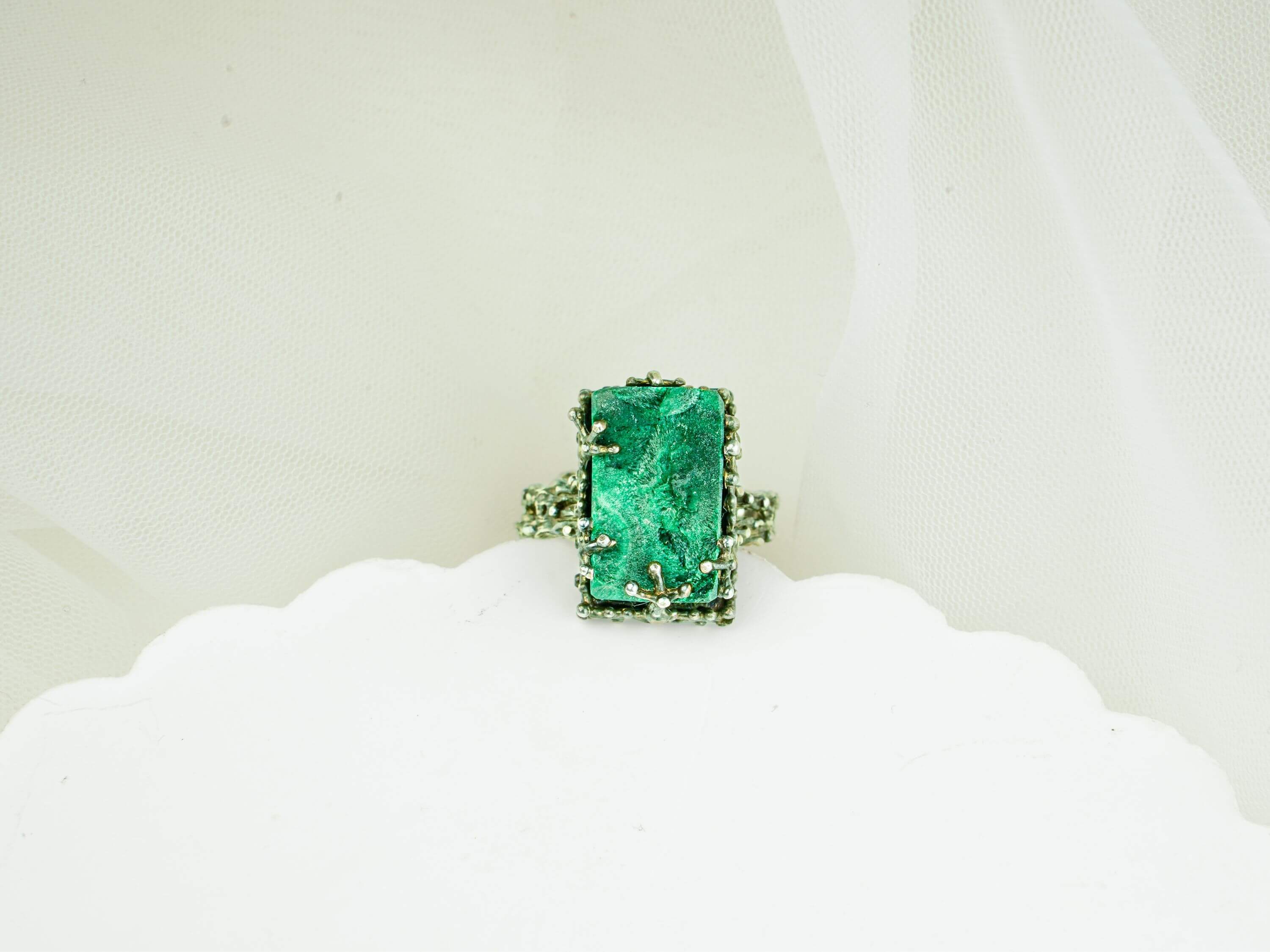 Close-up of natural green malachite texture and ornate handcrafted silver ring frame