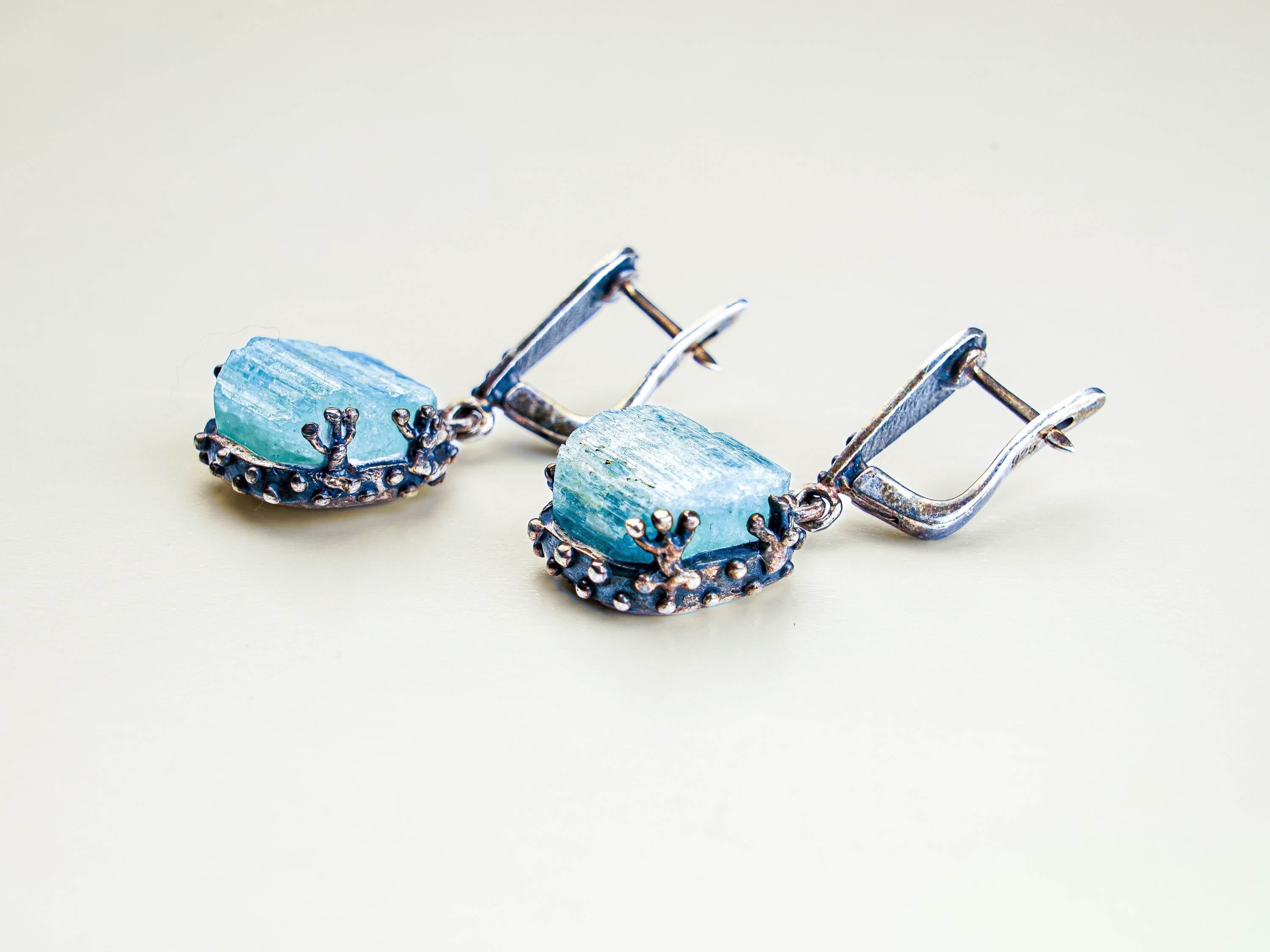 Close up aquamarine earrings raw crystal texture detail silver setting