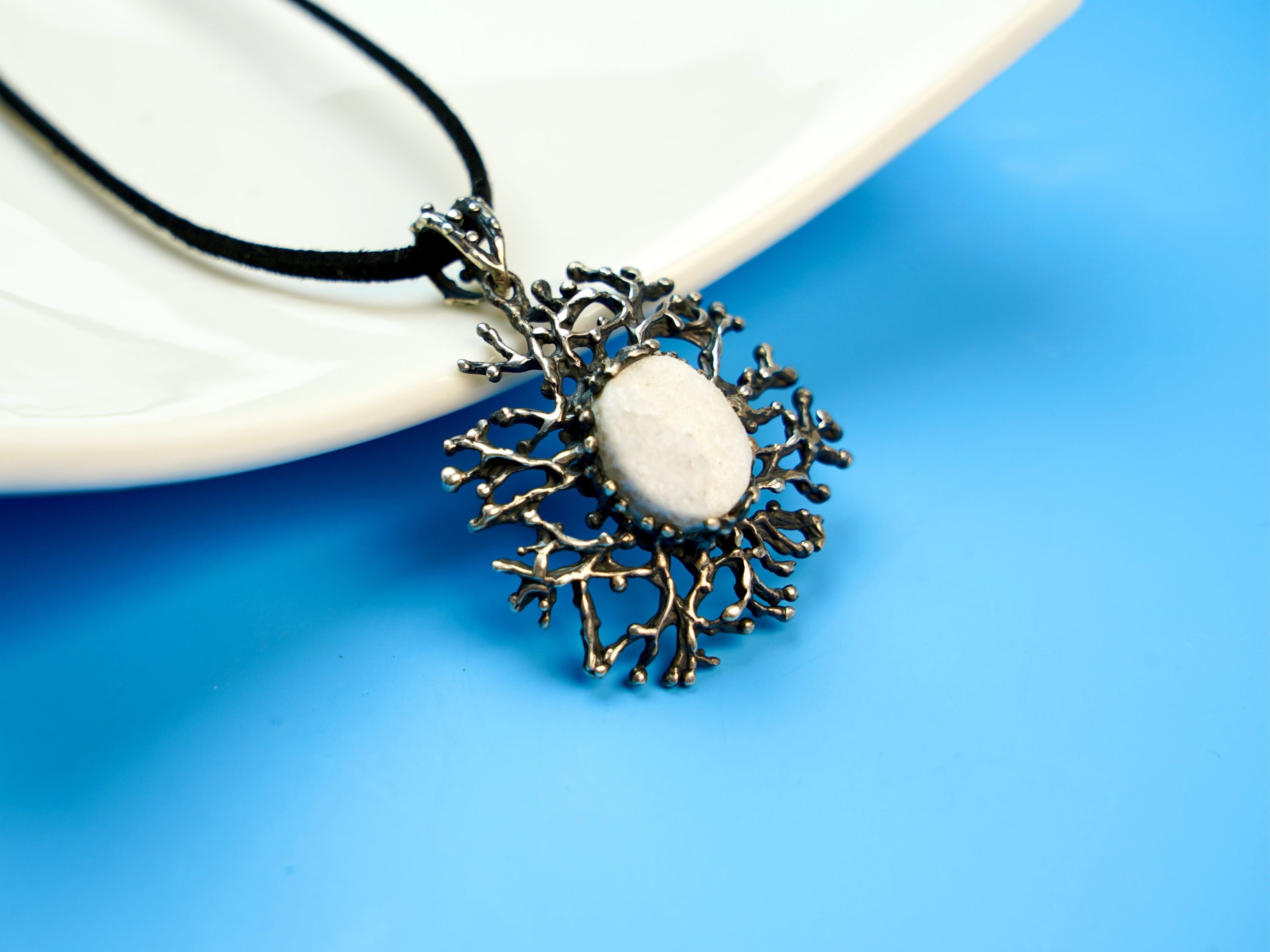moonstone pendant angled view, sculptural silver and glowing gemstone